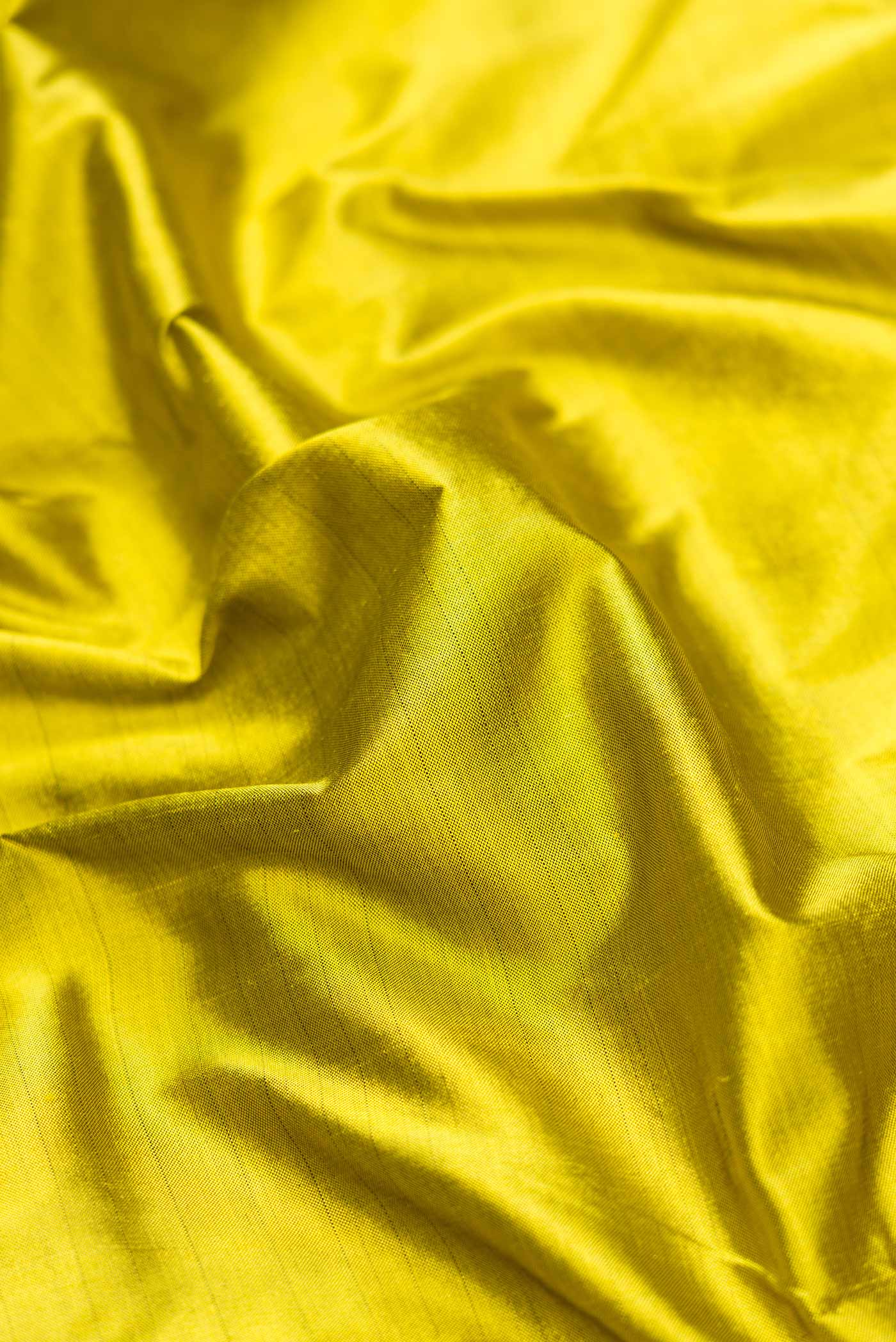 Close up of Parrot Green Dual Tone Double Ikat Saree with Plain Body and Zari Border.  displaying folds