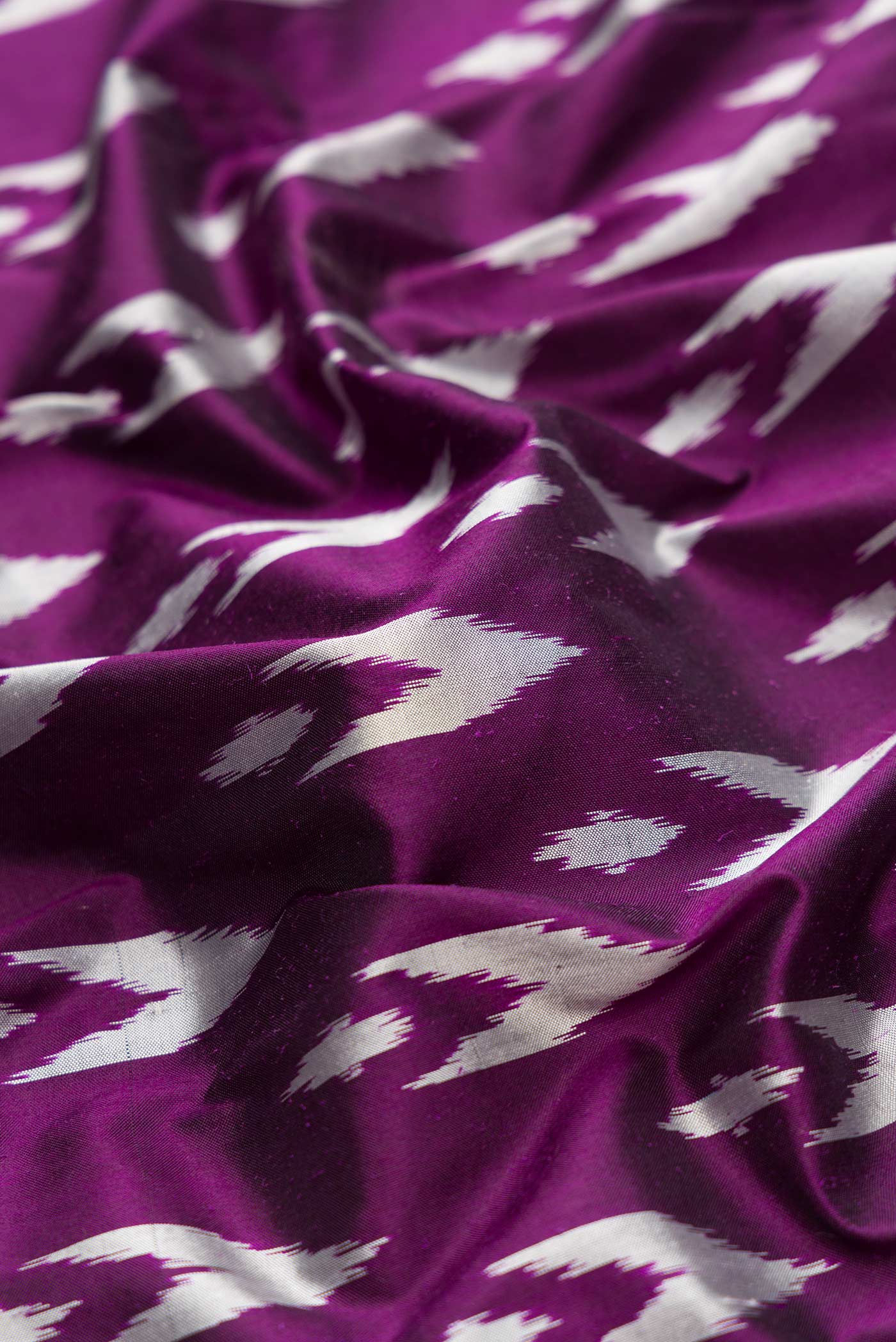 Close up of Burgundy Dual Tone Double Ikat Saree with Ikat Print on the body and Ikat Border.  displaying folds