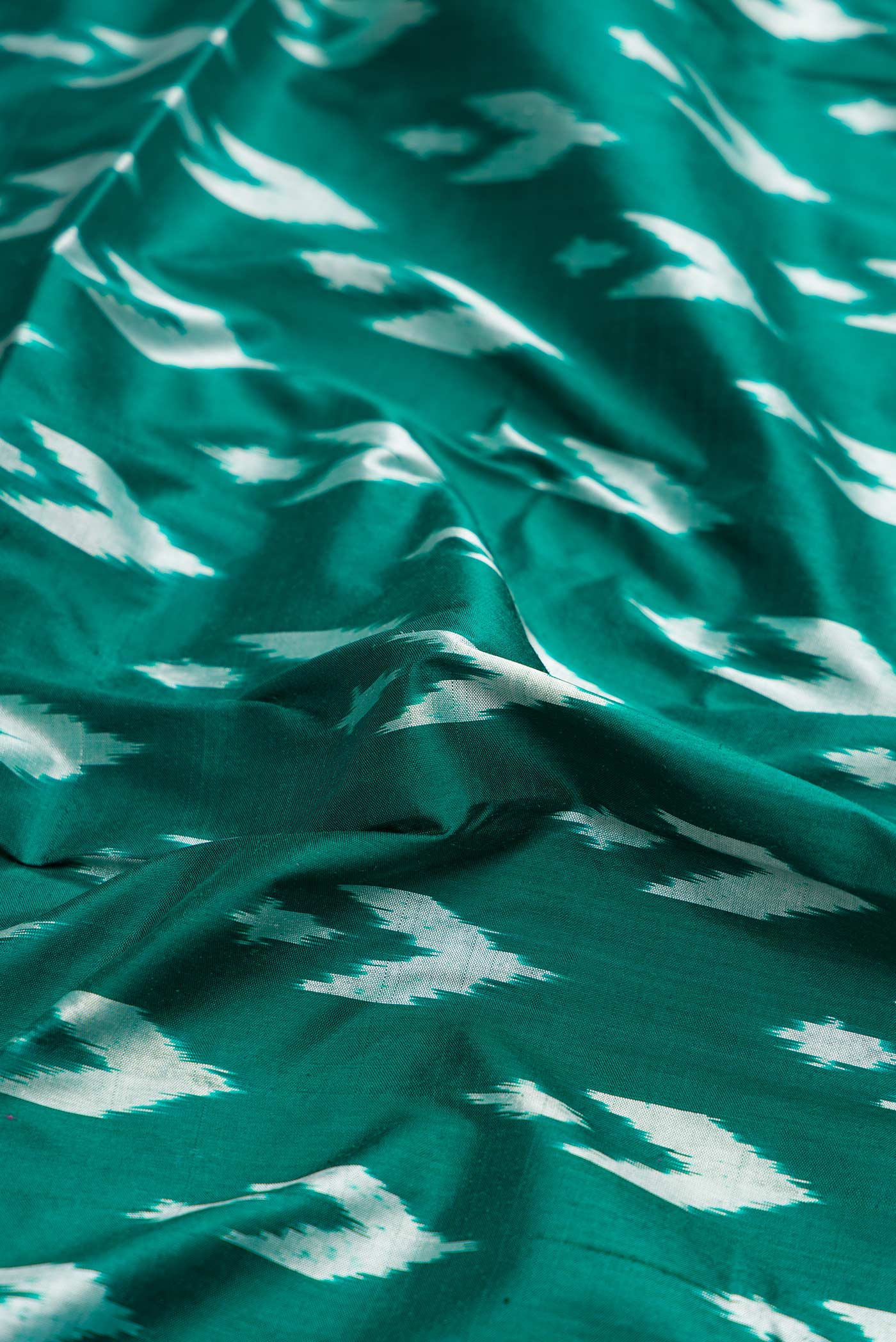 Close up of Green Dual Tone Double Ikat Saree with Ikat Print on the body and Ikat Border.  displaying folds