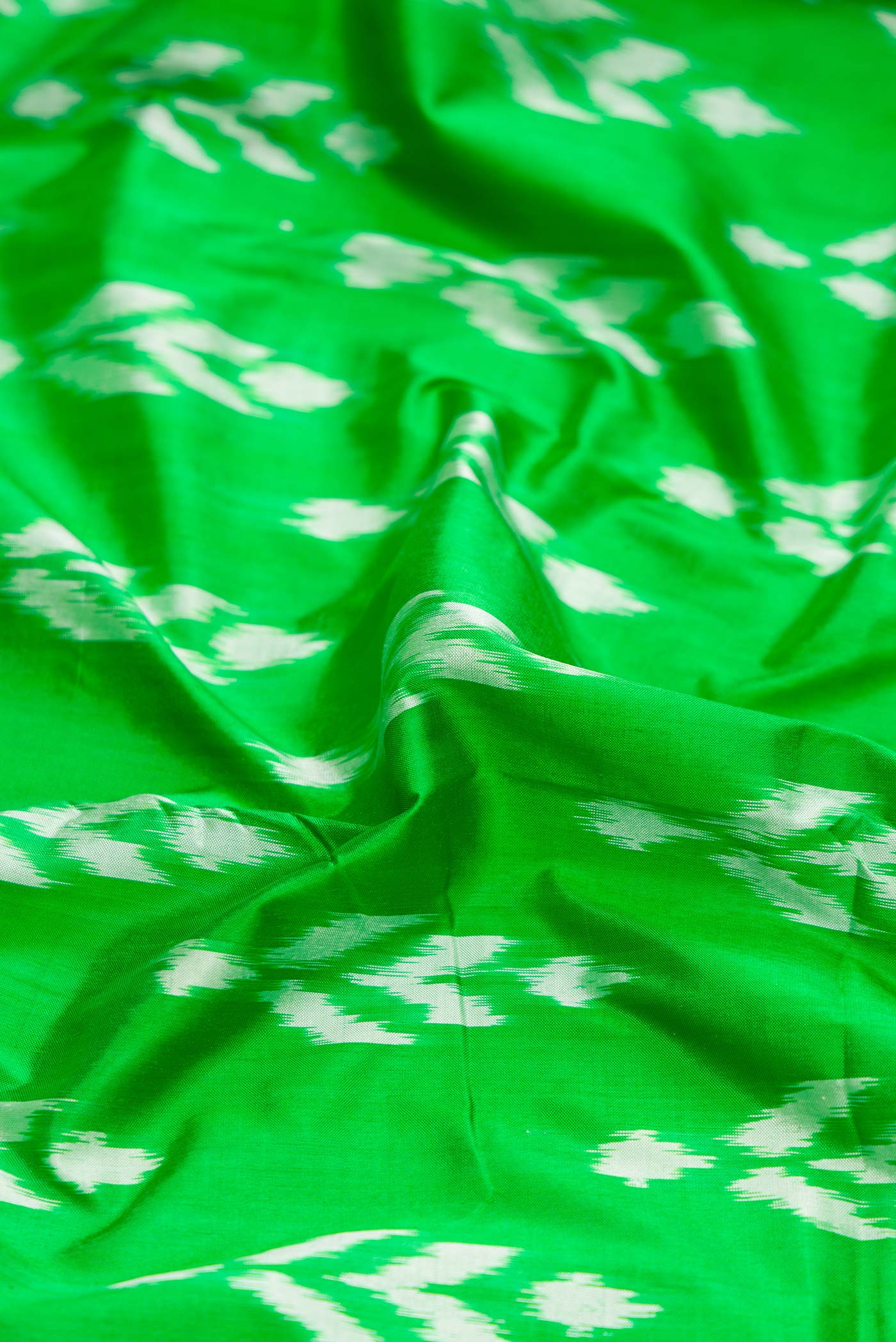 Close up of Green Dual Tone Double Ikat Saree with Ikat Print on the body and Ikat Border.  displaying folds