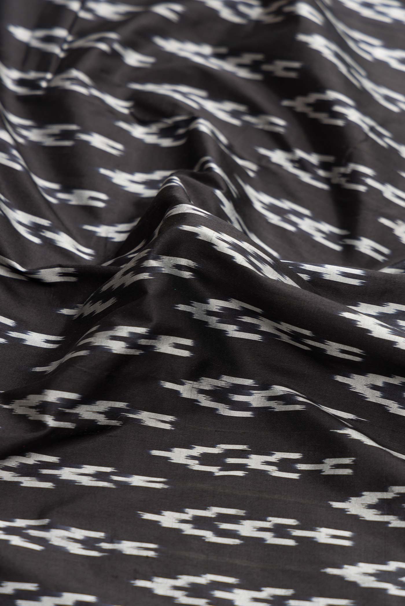 Close up of Black Dual Tone Double Ikat Saree with Ikat Print on the body and Ikat Border.  displaying folds