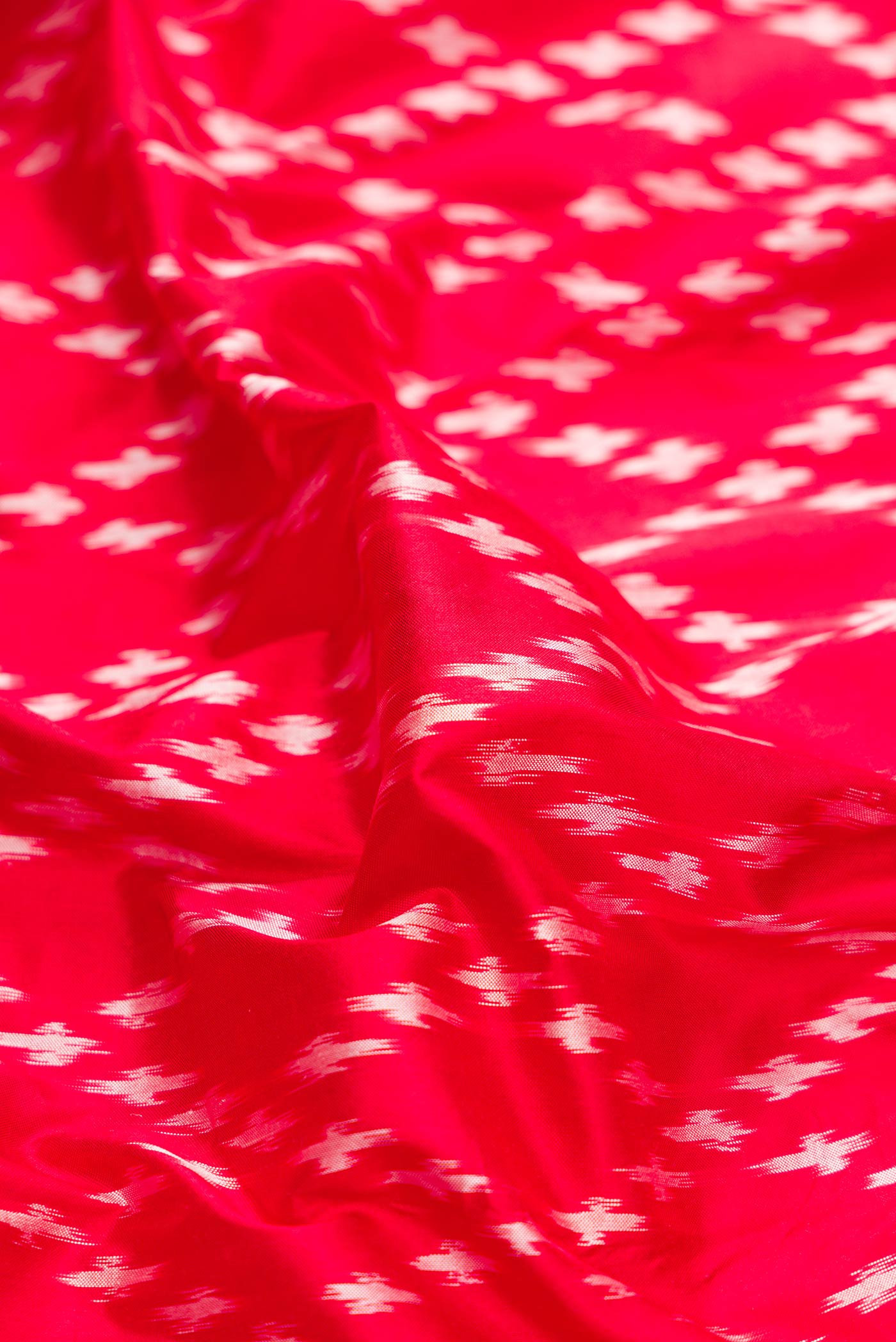 Close up of Red Dual Tone Double Ikat Saree with Ikat Print on the body and Zari Border.  displaying folds