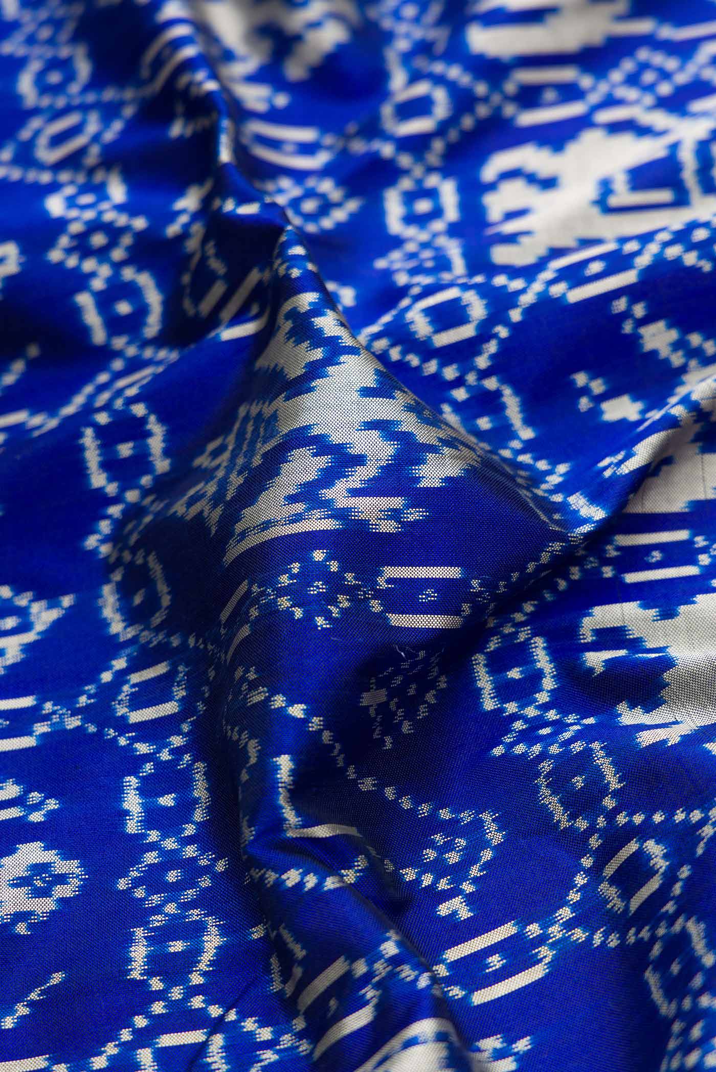 Close up of Royal Blue Dual Tone Double Ikat Saree with Ikat Print on the body and Zari Border.  displaying folds