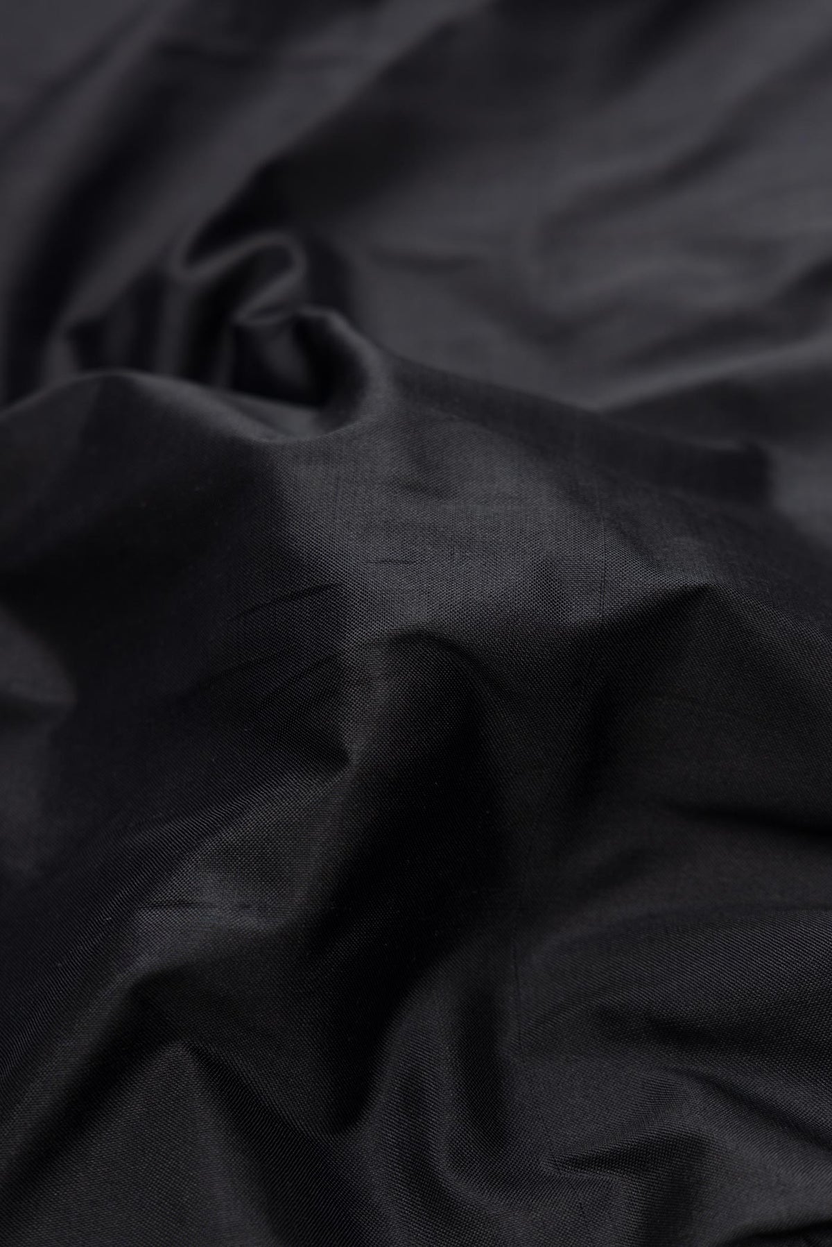 Close up of Black Dual Tone Double Ikat Saree with Plain Body and Ikat Border.  displaying folds