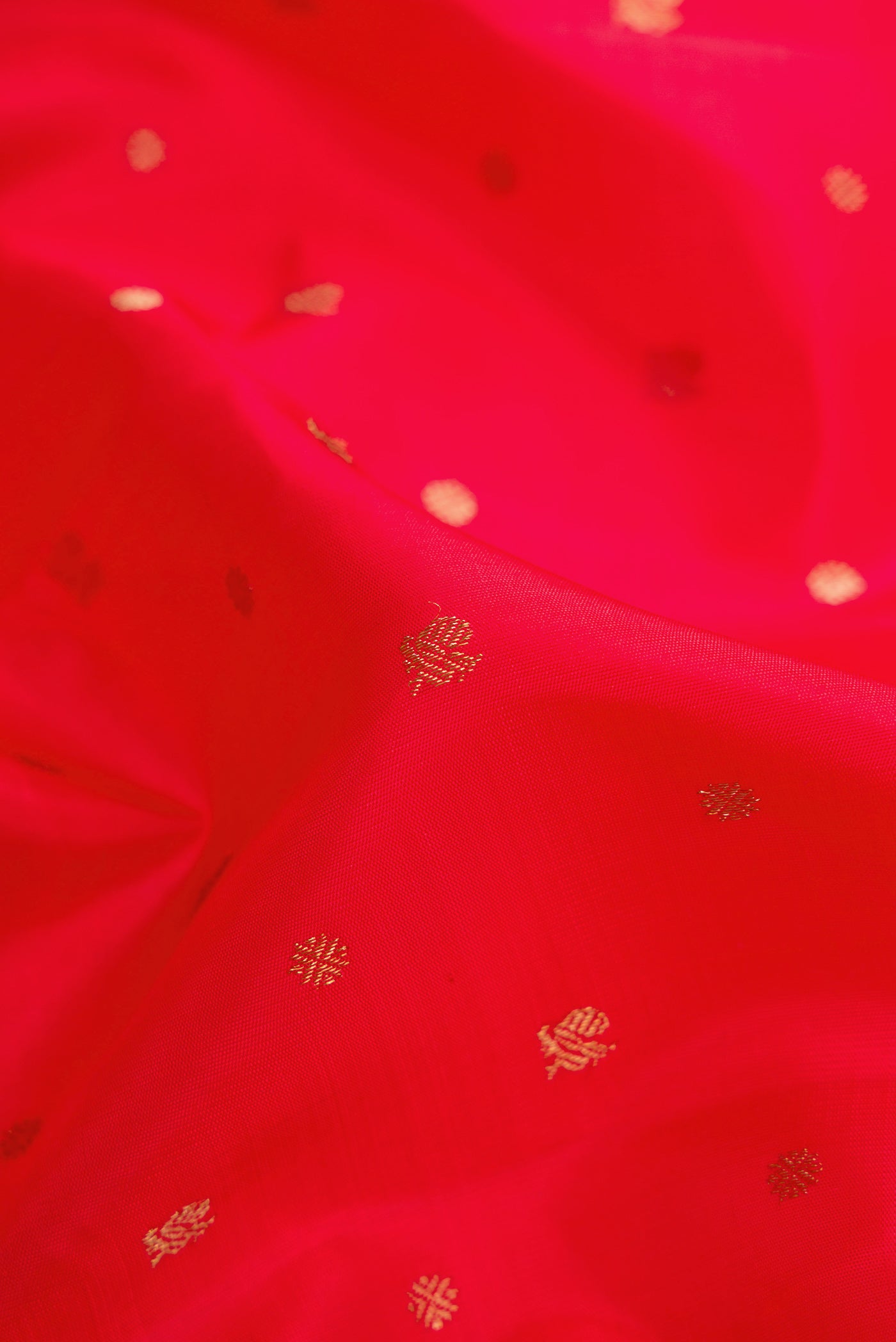 Close up of Pure Silk Pure Zari Red Dual Tone Kanchipuram Saree with Zari Butta on the body and Zari Border.  displaying folds