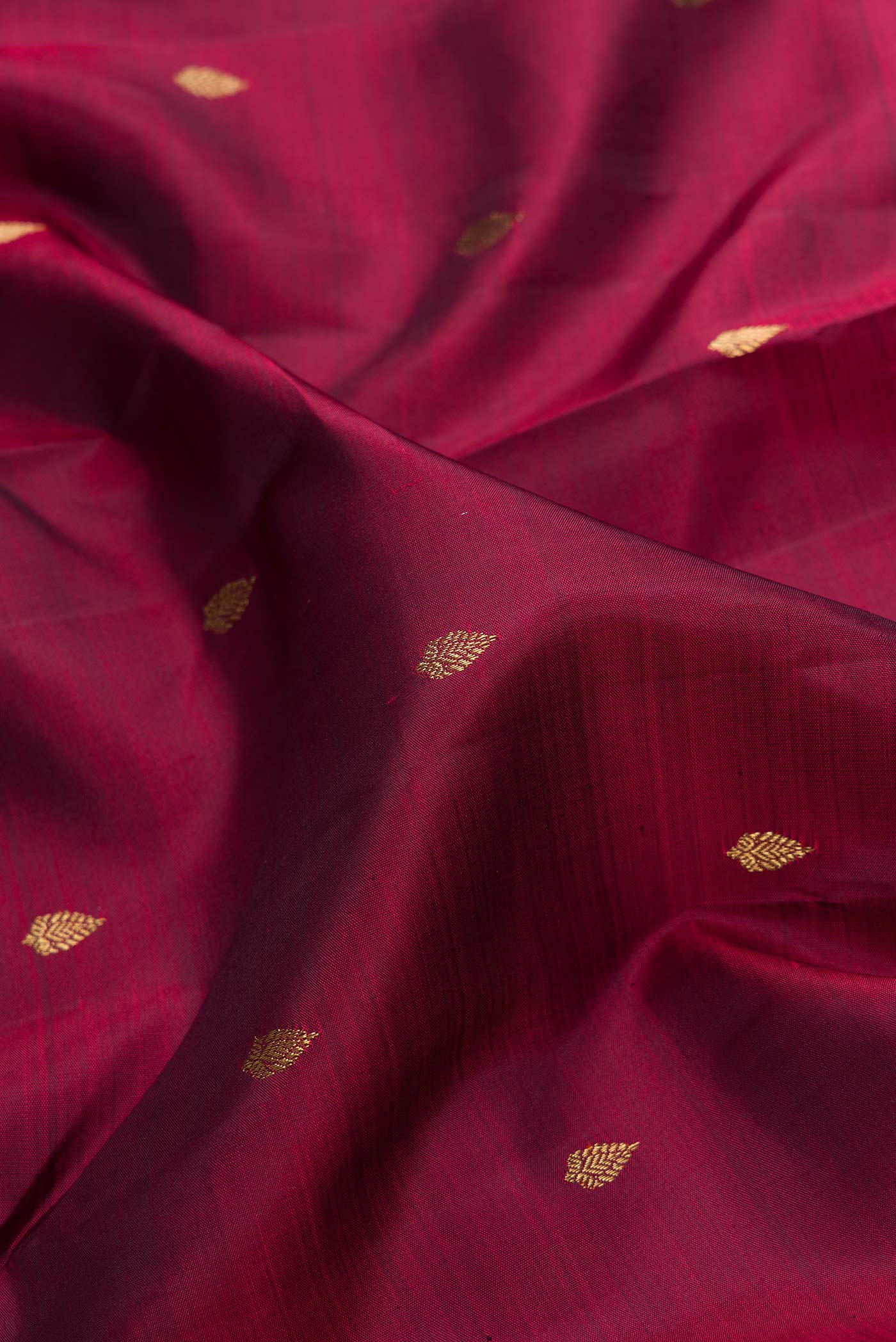 Close up of Pure Silk Pure Zari Burgundy Dual Tone Kanchipuram Saree with Zari Butta on the body and Zari Border.  displaying folds