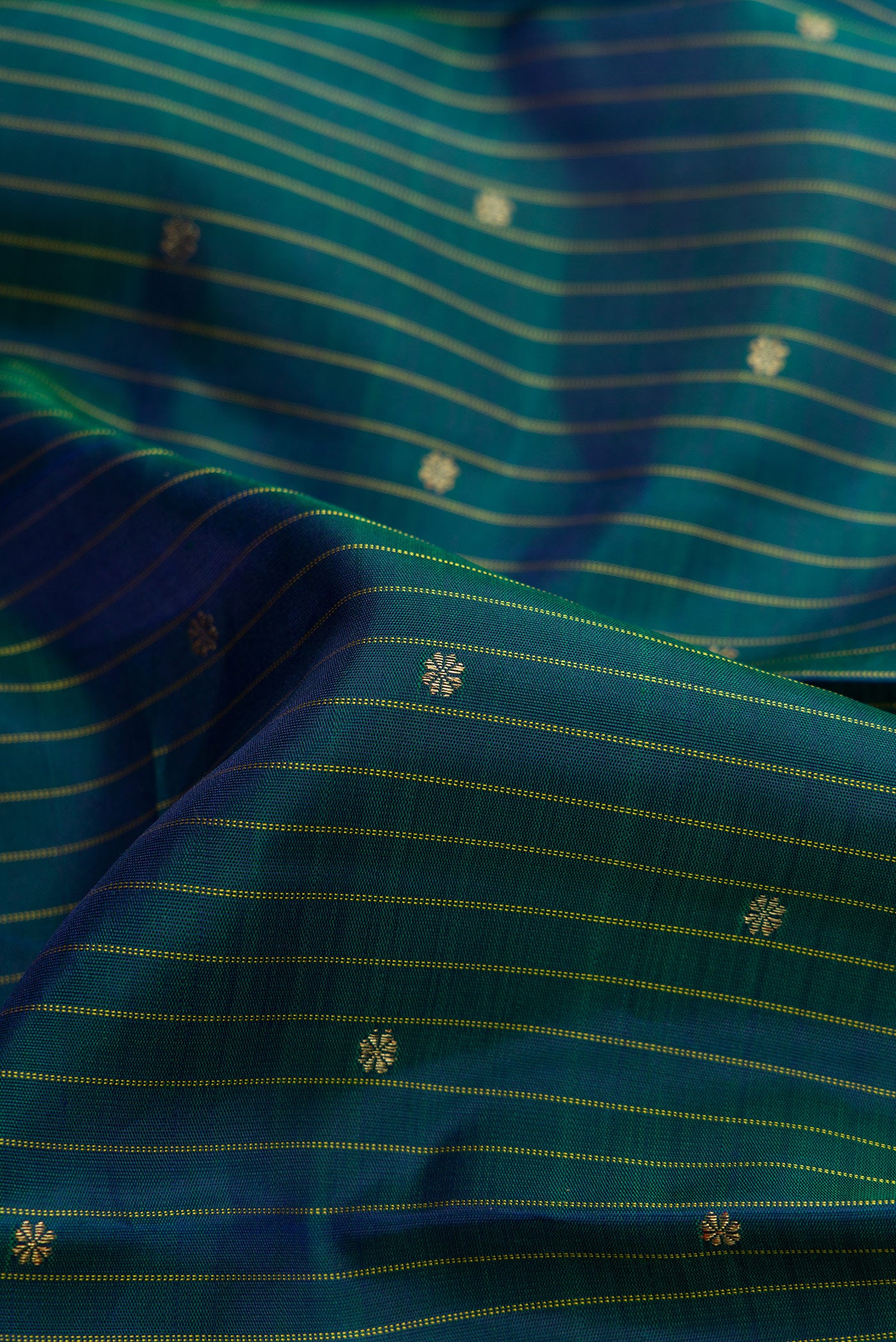 Close up of Pure Silk Pure Zari Bottle Green Dual Tone Kanchipuram Saree with Checked design on the body and Zari Border.  displaying folds