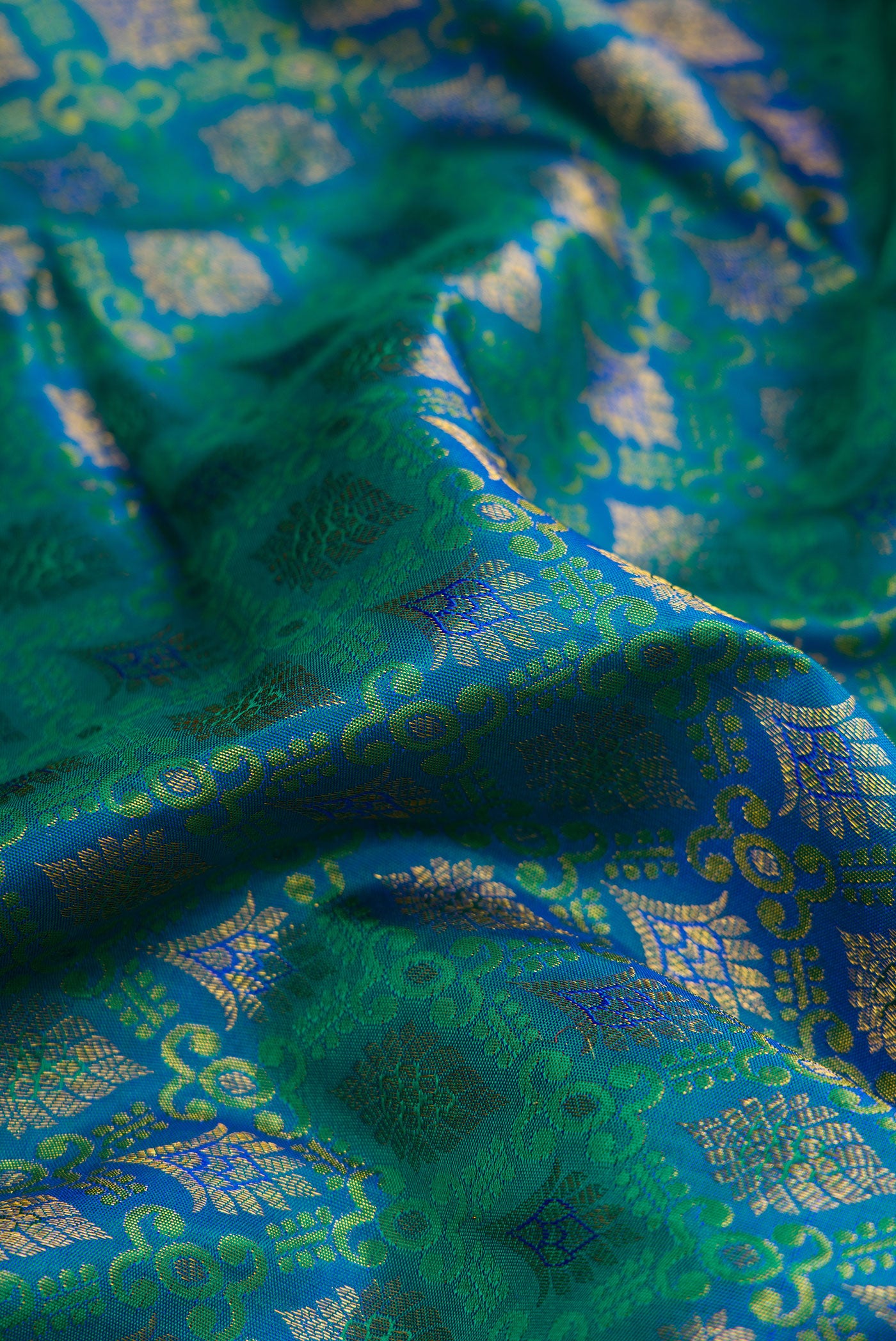 Close up of Peacock Blue Dual Tone Kanjivaram Silk Saree with Zari Brocade on the body and Zari Border.  displaying folds
