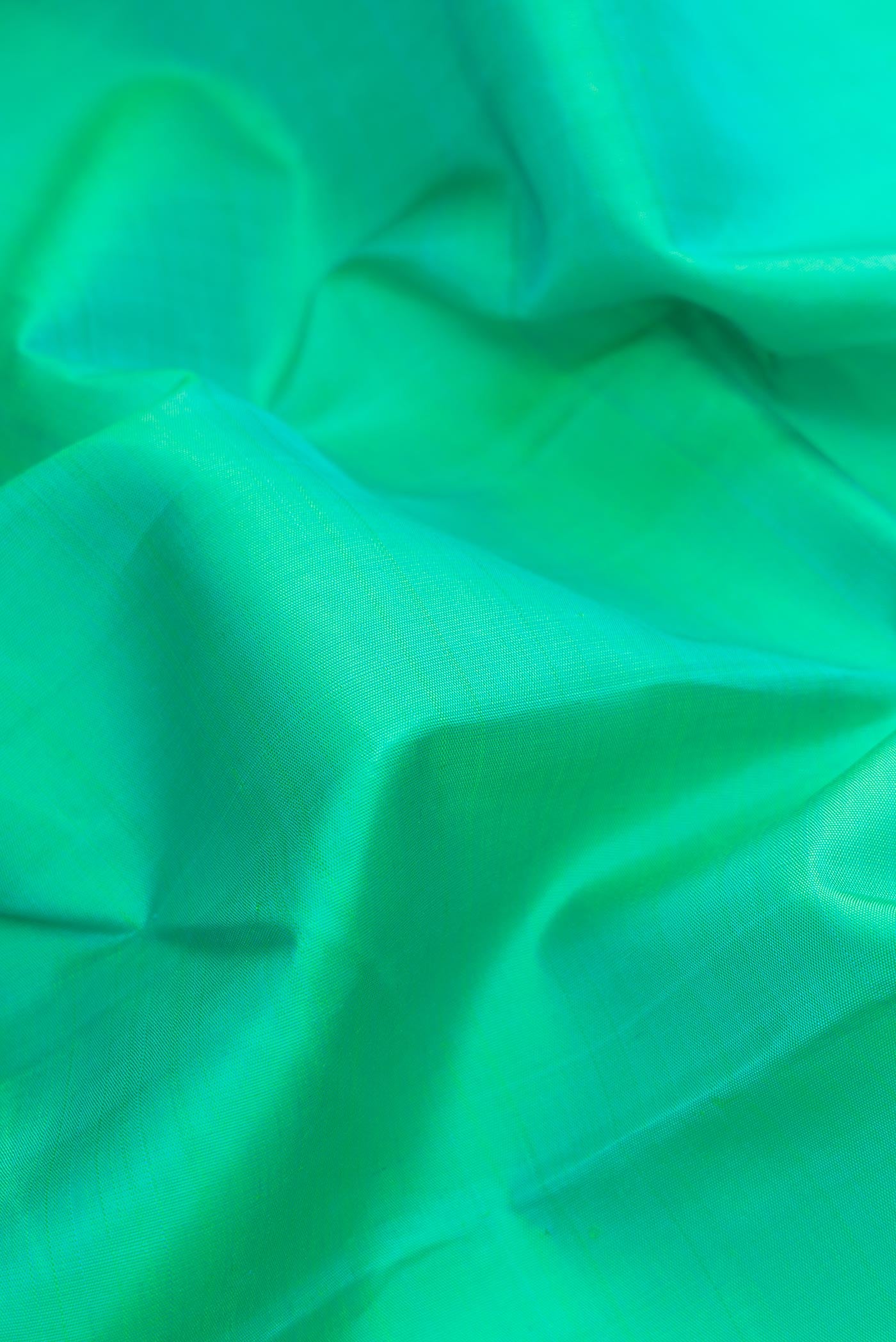 Close up of Sea Green Dual Tone Kanchipuram Silk Saree with Plain Body and Zari Border.  displaying folds