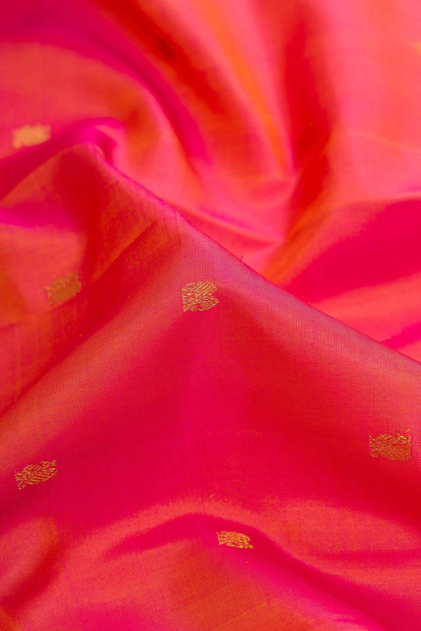 Close up of Coral Dual Tone Kanchipuram Silk Saree with Zari Butta on the body and Zari Border.  displaying folds