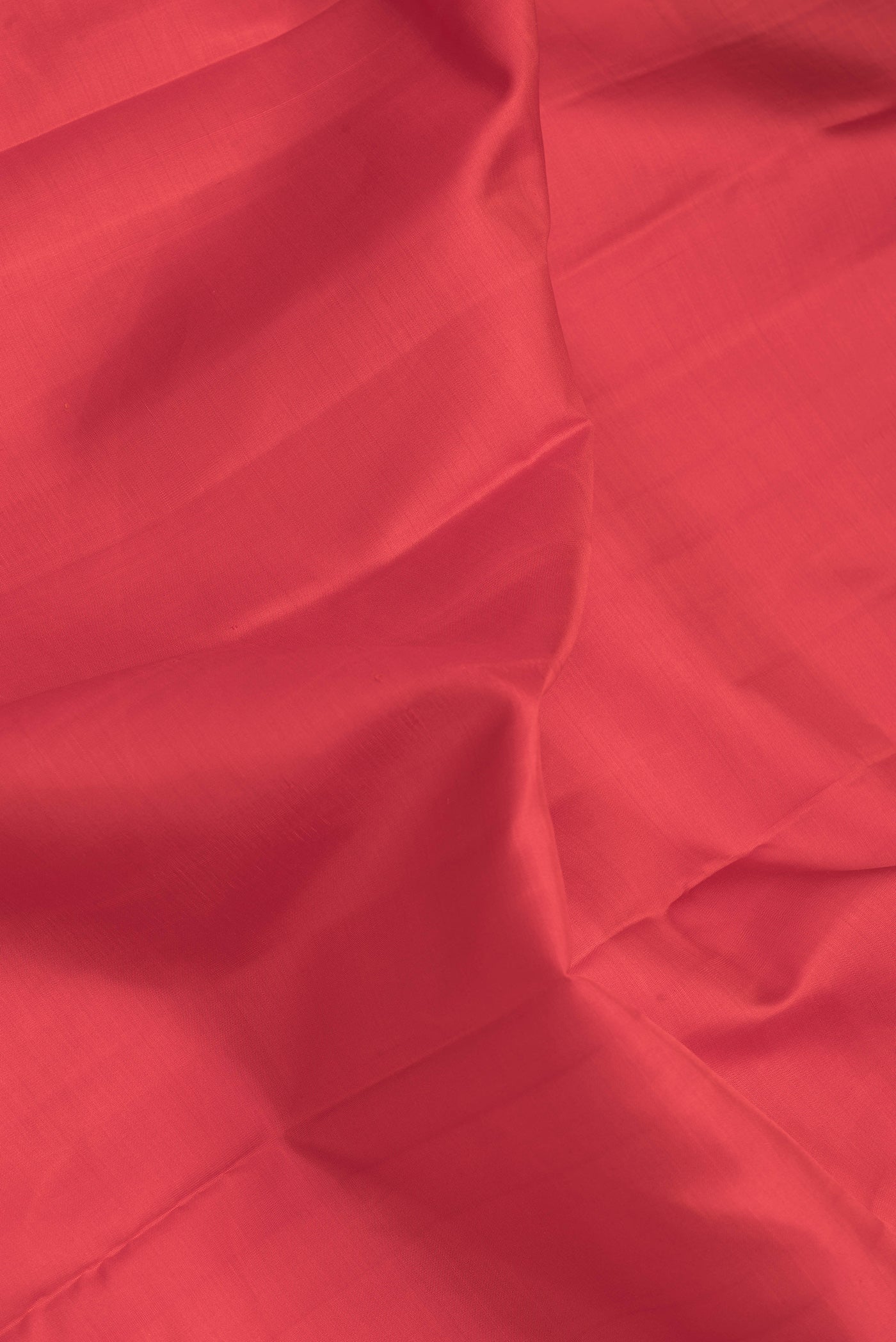 Close up of Red Dual Tone Kanchipuram Silk Saree with Plain Body and Zari Border.  displaying folds