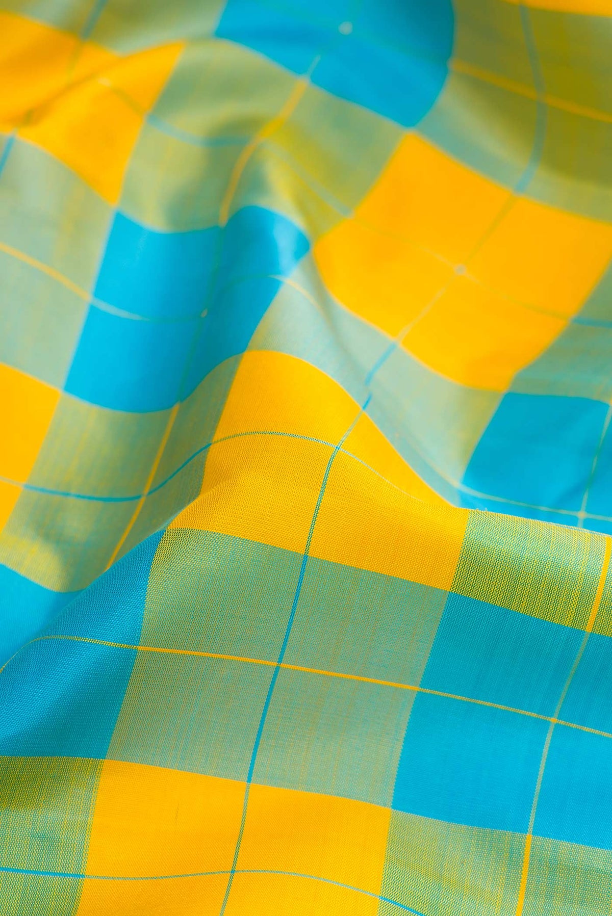 Close up of Yellow and Sky Blue Color Kanchipuram Silk Saree with Checked design on the body and Zari Border.  displaying folds