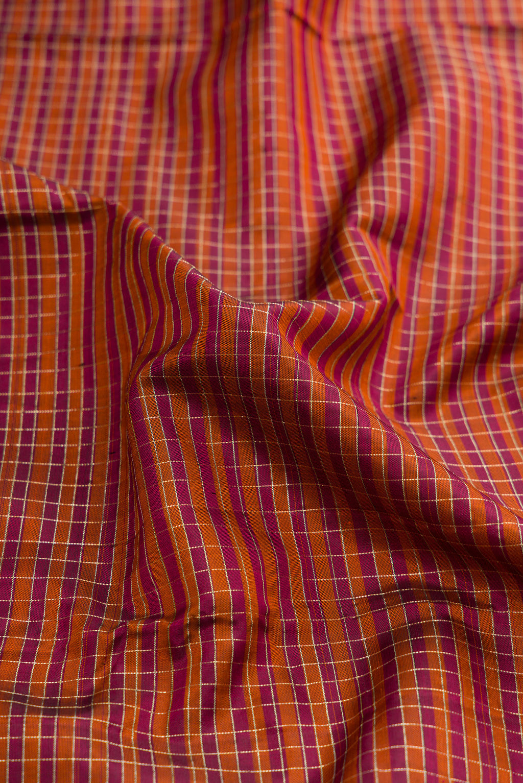 Close up of Orange Dual Tone Kanjivaram Silk Saree with Checked design on the body and Zari Border.  displaying folds