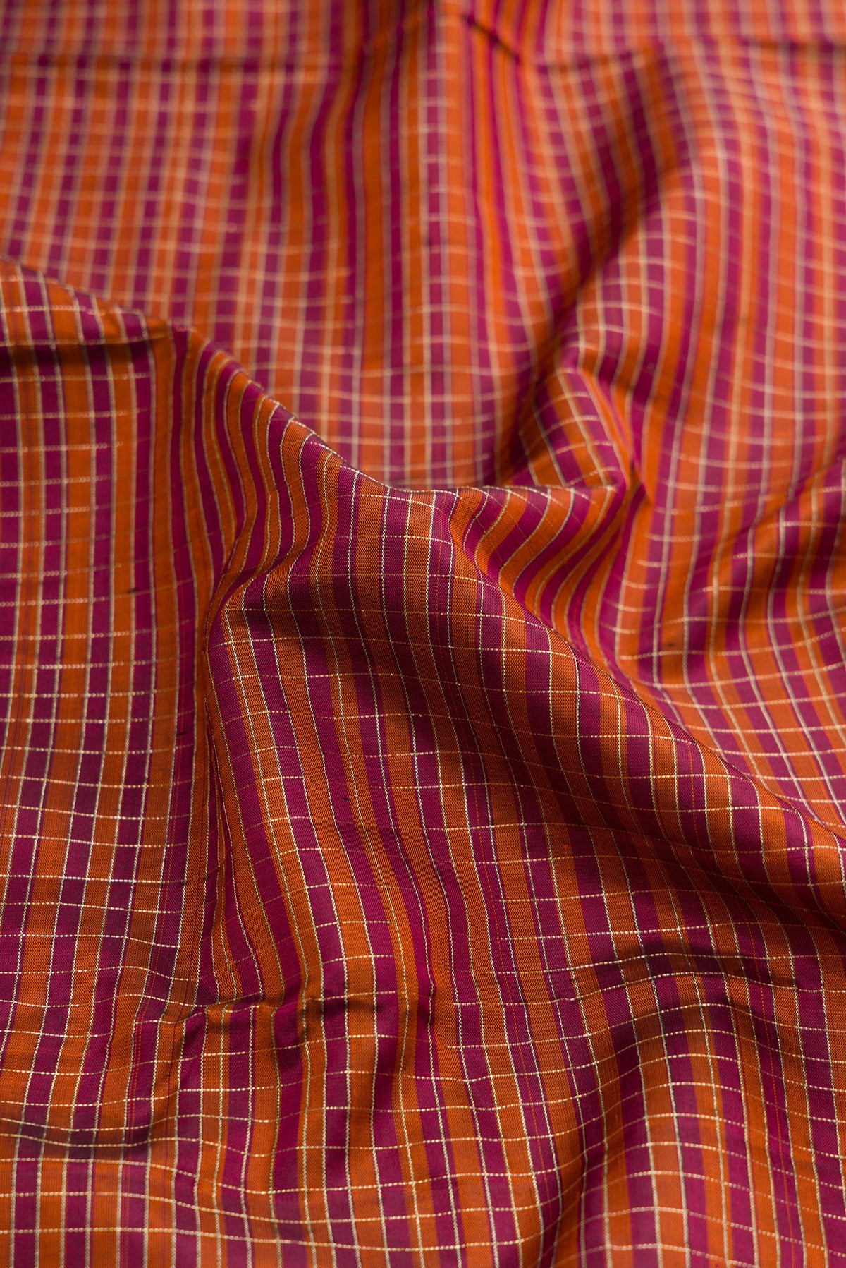 Close up of Orange Dual Tone Kanjivaram Silk Saree with Checked design on the body and Zari Border.  displaying folds