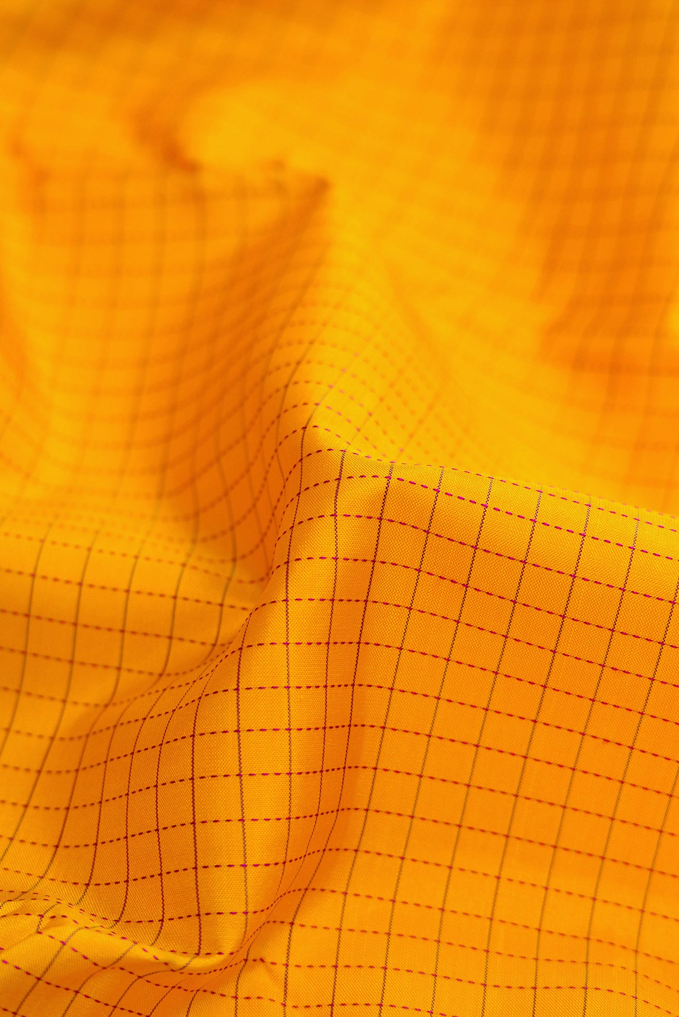 Close up of Mustard Dual Tone Kanjivaram Silk Saree with Checked design on the body and Zari Border.  displaying folds