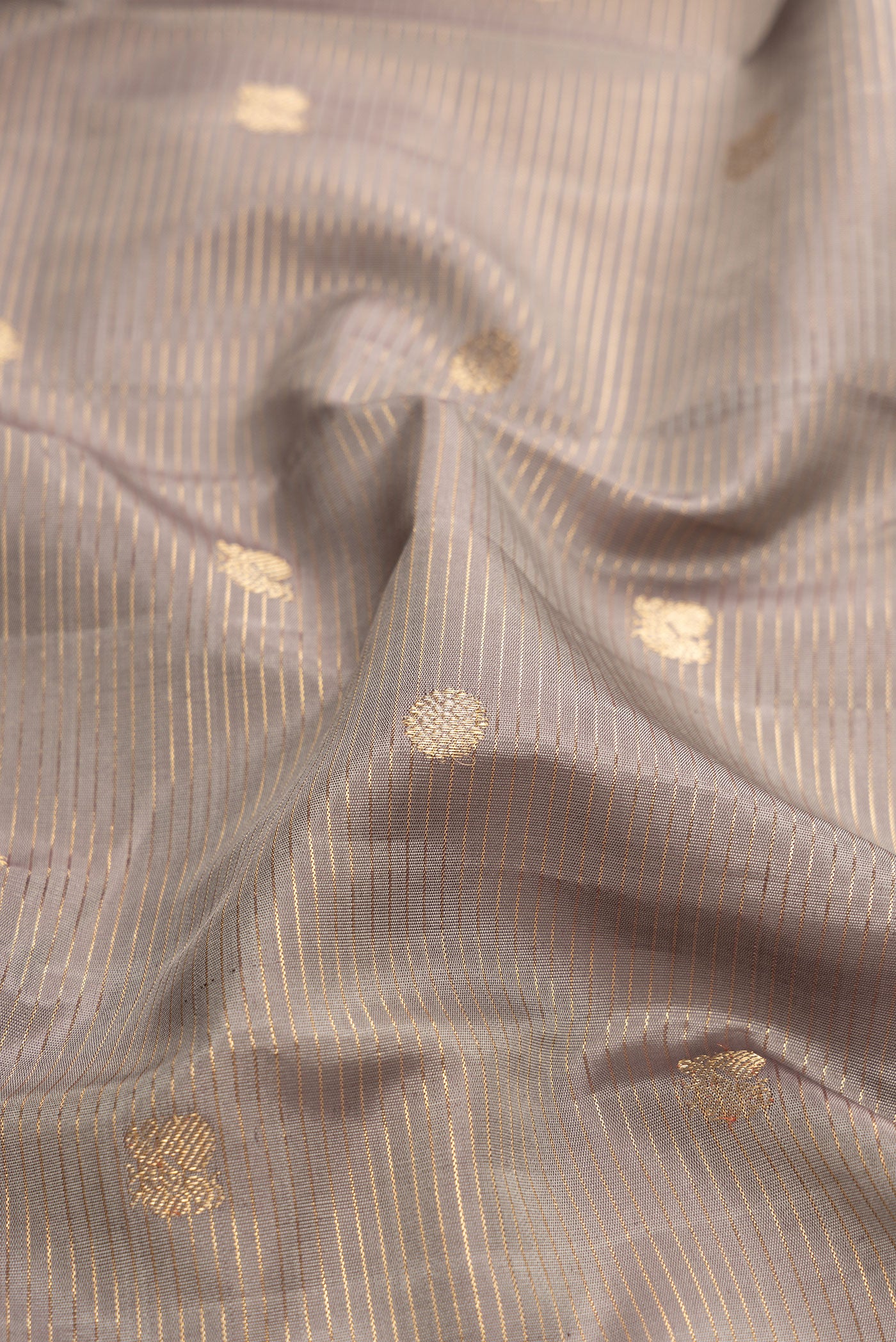 Close up of Grey Dual Tone Kanjivaram Silk Saree with Zari Butta on the body and Zari Border.  displaying folds