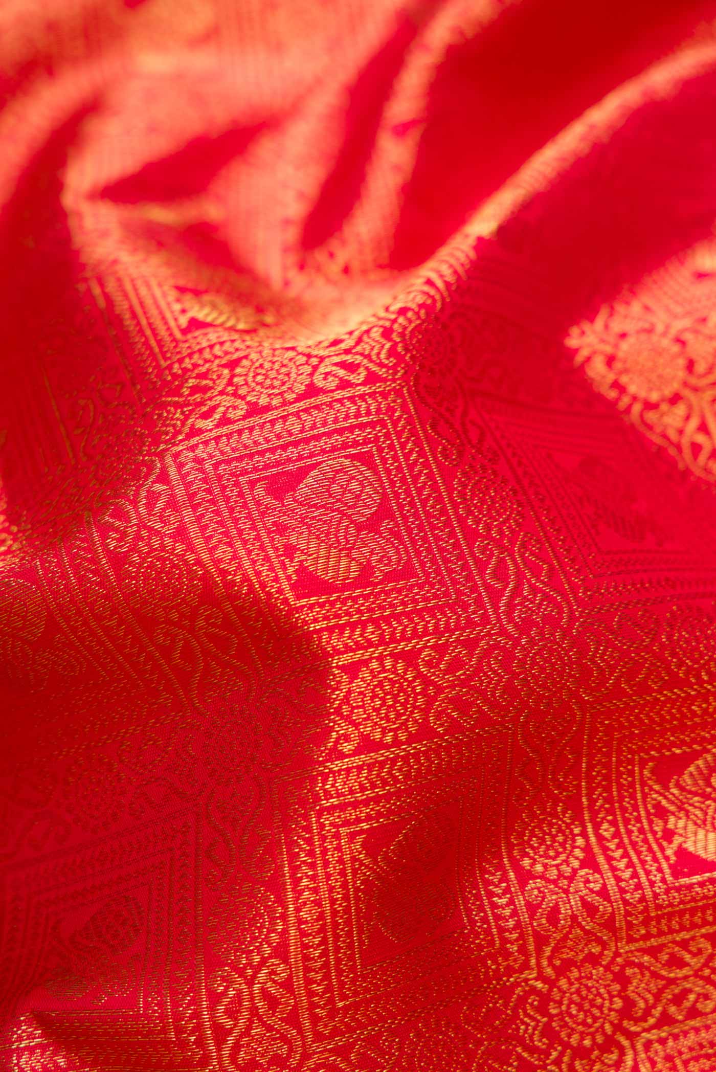 Close up of Pure Silk Pure Zari Red Dual Tone Kanchipuram Saree with Zari Brocade on the body and Zari Border displaying folds
