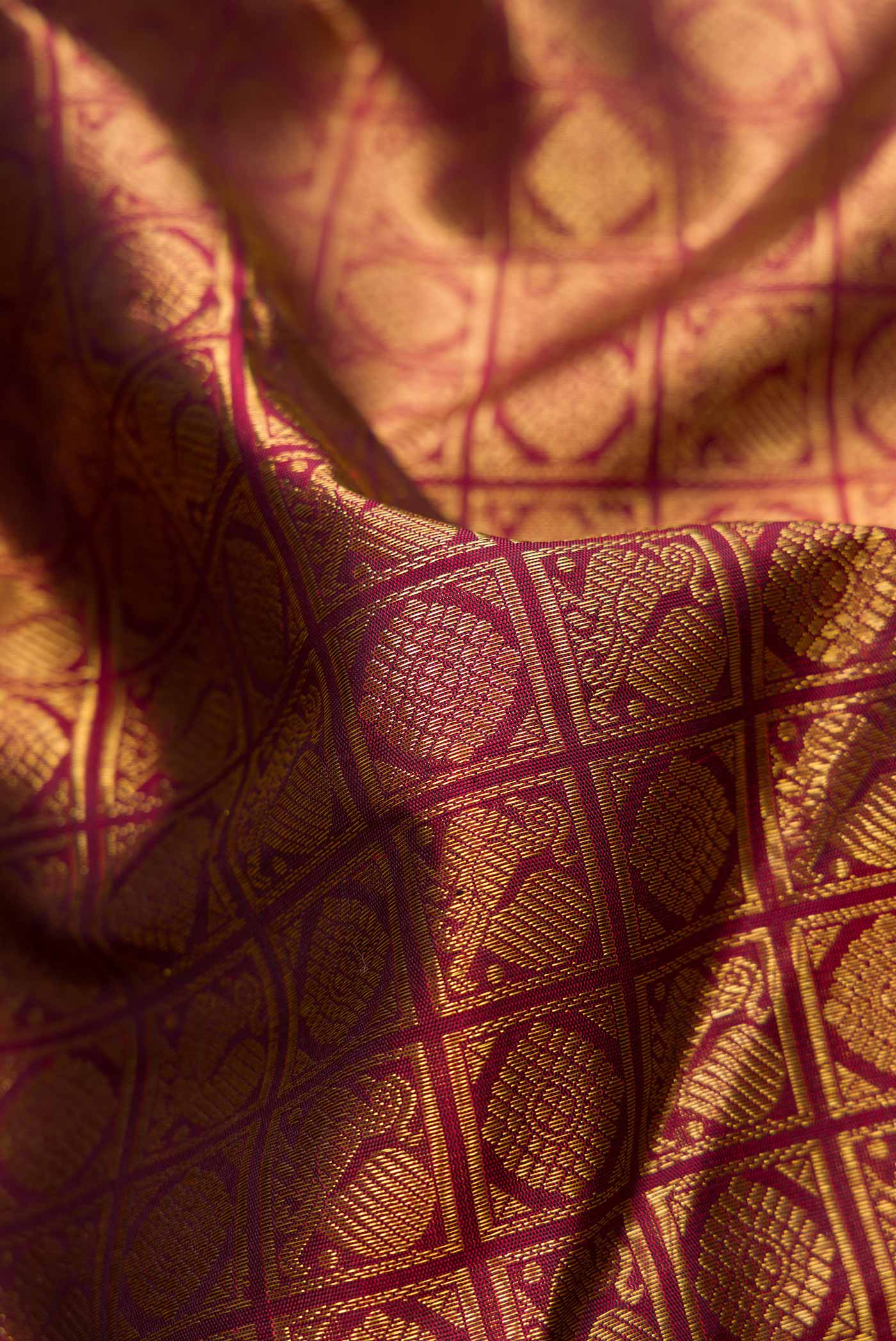 Close up of Pure Silk Pure Zari Maroon Dual Tone Kanchipuram Saree with Zari Brocade on the body and Zari Border displaying folds
