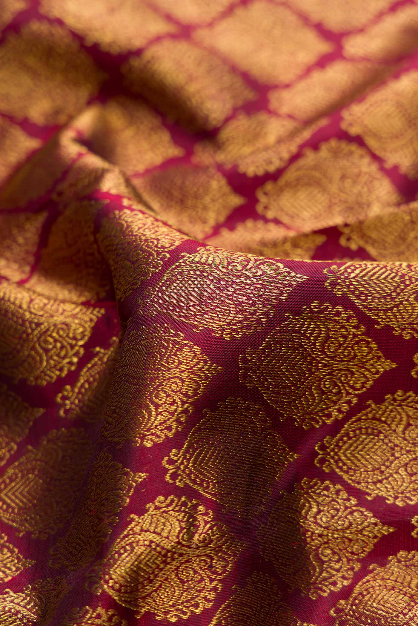 Close up of Pure Silk Pure Zari Maroon Dual Tone Kanchipuram Saree with Zari Brocade on the body and Zari Border displaying folds