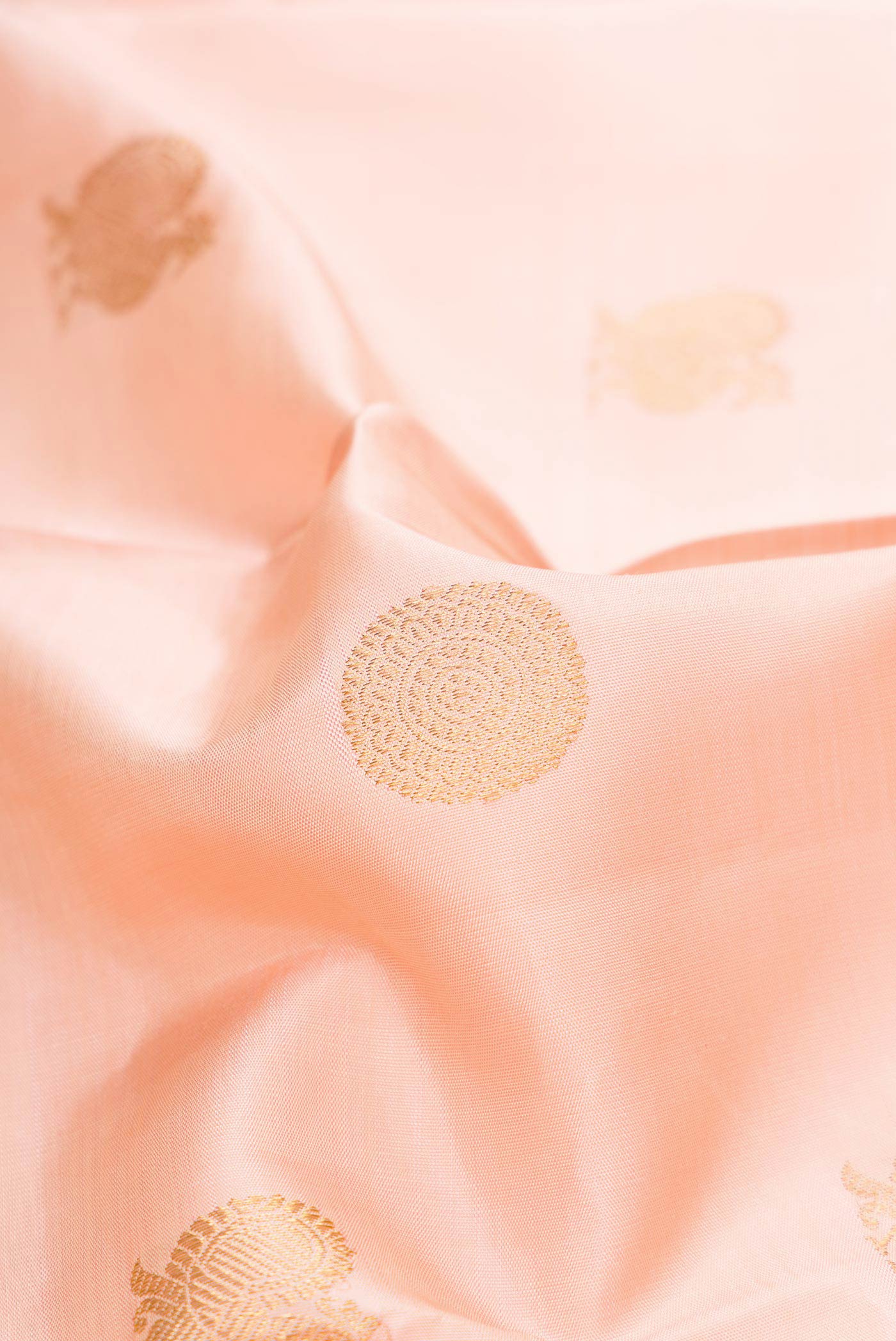 Close up of Pure Silk Pure Zari Rose Gold Dual Tone Kanjivaram Saree with Zari Butta on the body and Zari Border.  displaying folds