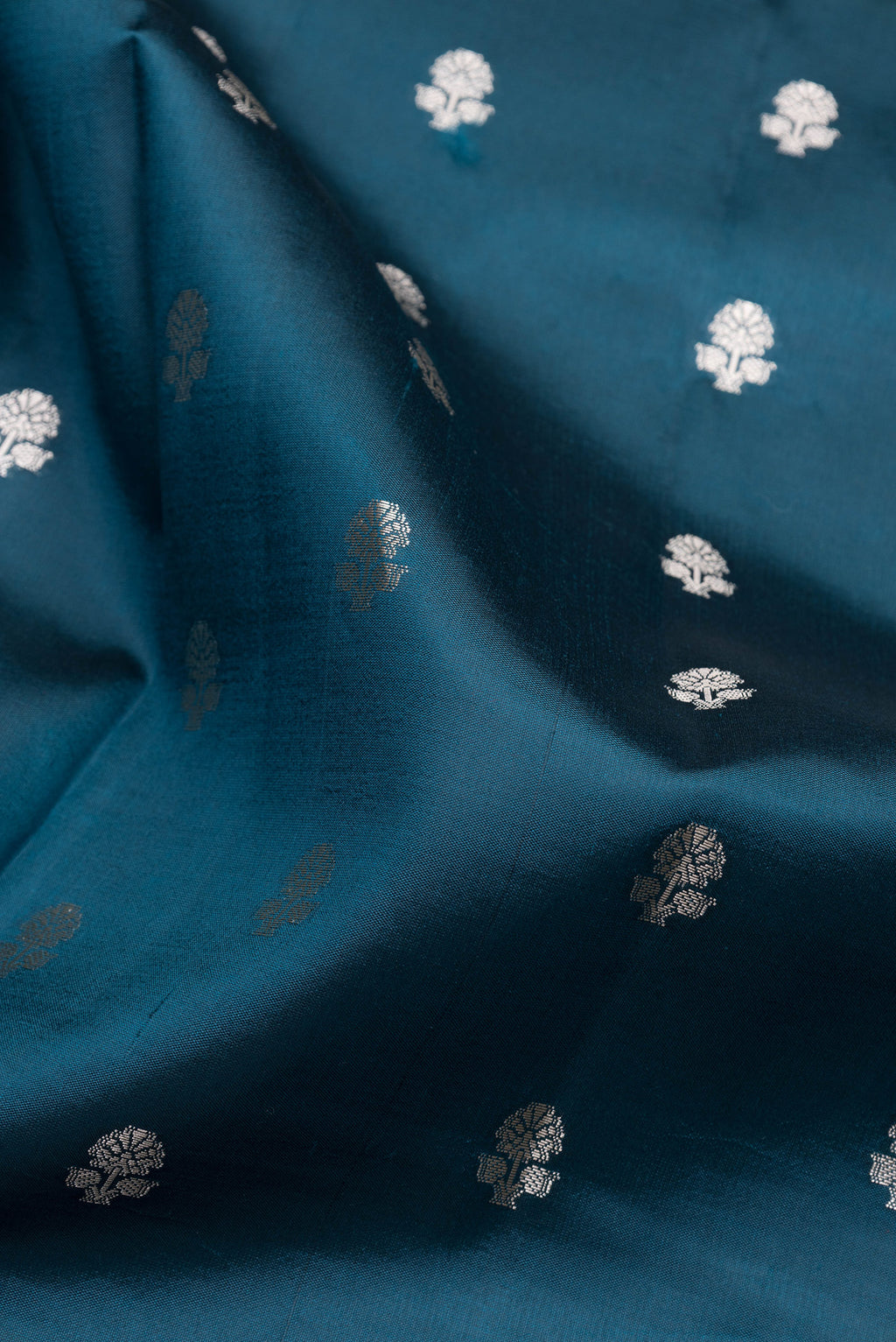 Close up of Peacock Blue Dual Tone Tussar Silk Saree with Zari Butta on the body and Fancy Border.  displaying folds