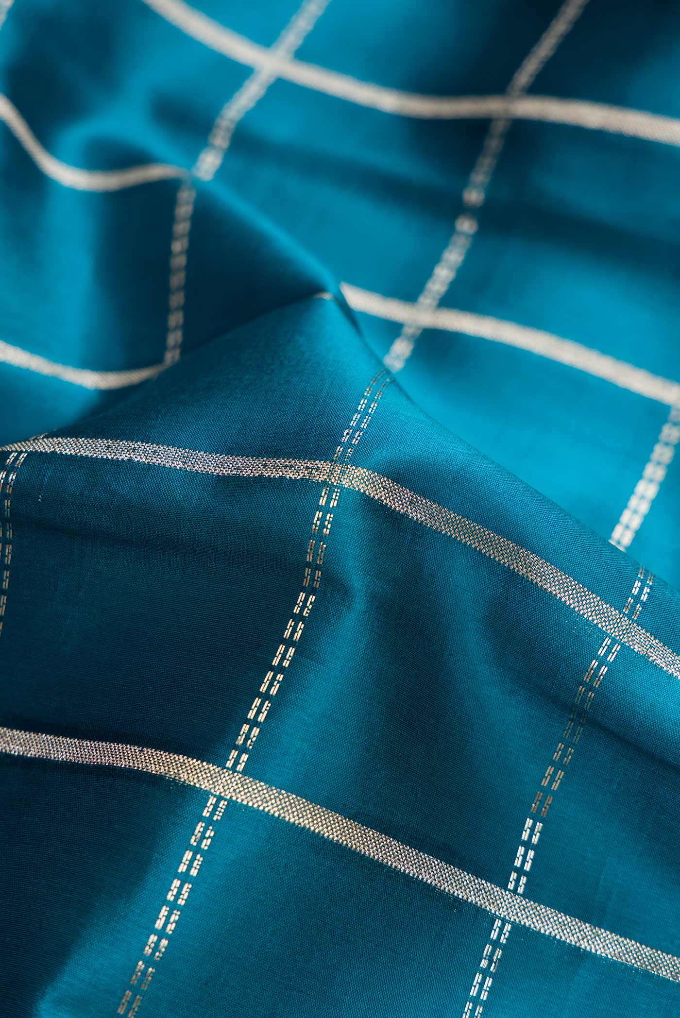 Close up of Peacock Blue Dual Tone Tussar Silk Saree with Checked design on the body and Zari Border.  displaying folds