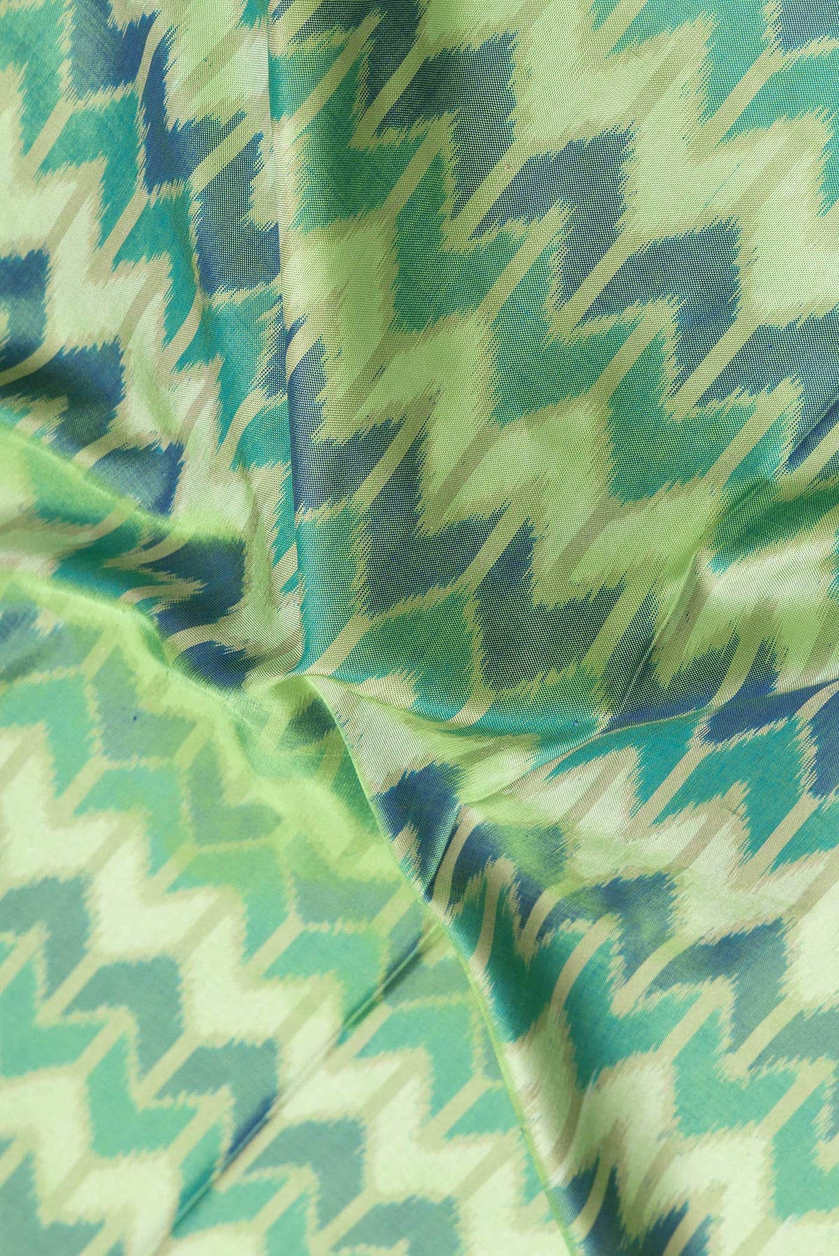 Close up of Green Dual Tone Double Ikat Saree with Ikat Print on the body and Zari Border.  displaying folds