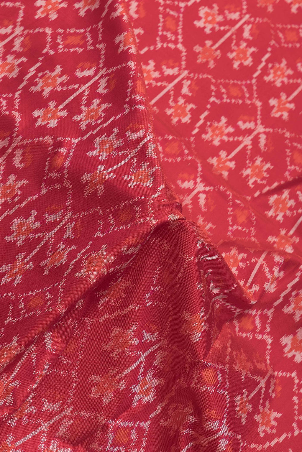Close up of Red Dual Tone Double Ikat Saree with Ikat Print on the body and Plain Border.  displaying folds