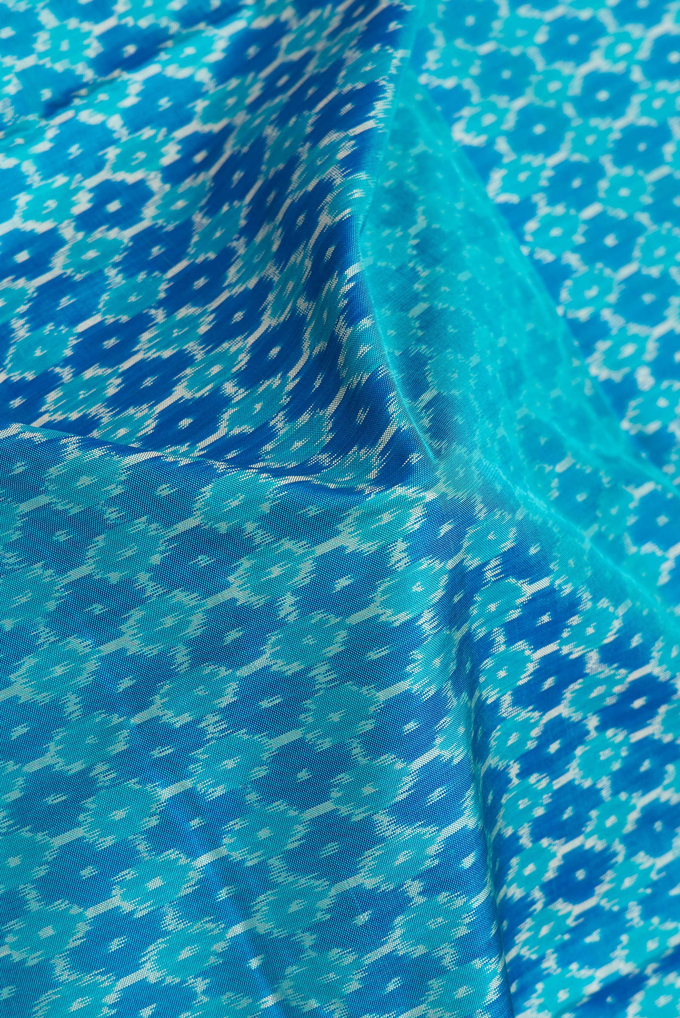 Close up of Sky Blue Dual Tone Double Ikat Saree with Ikat Print on the body and Plain Border.  displaying folds