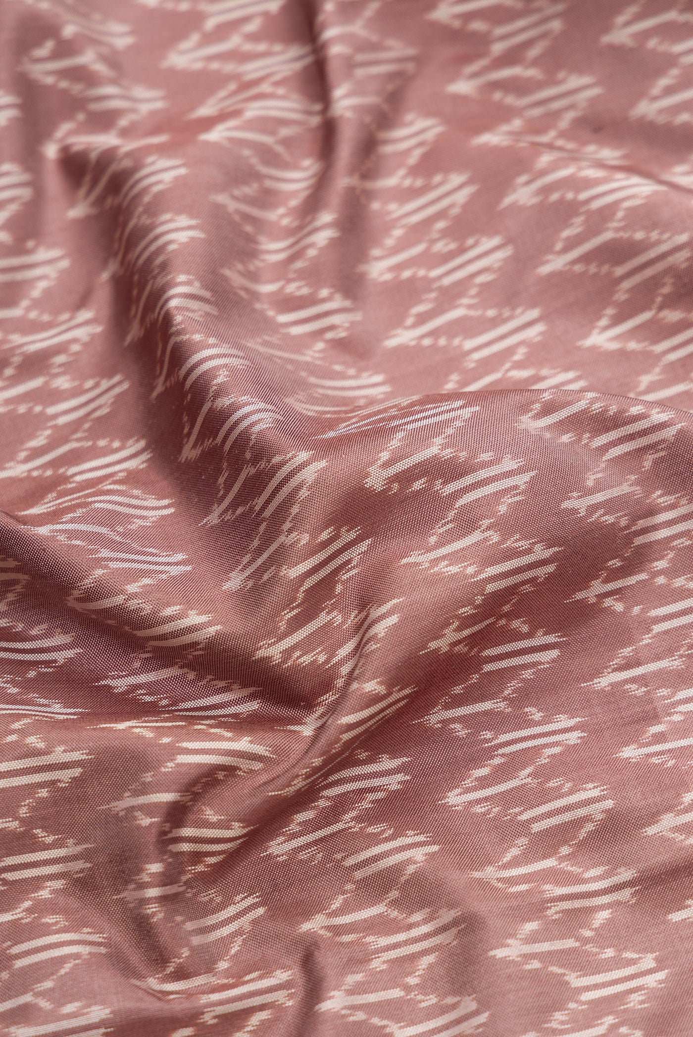 Close up of Brown Dual Tone Double Ikat Saree with Ikat Print on the body and Zari Border.  displaying folds