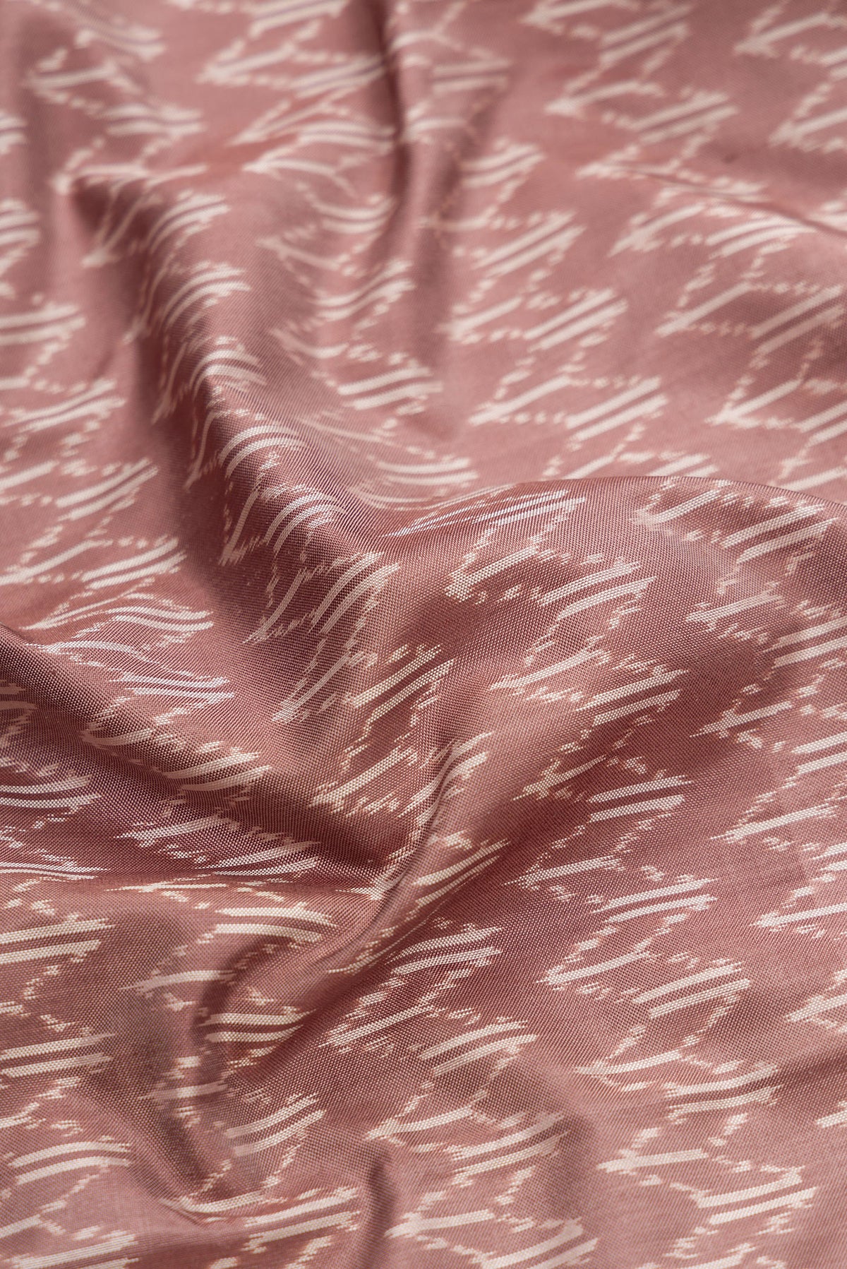 Close up of Brown Dual Tone Double Ikat Saree with Ikat Print on the body and Zari Border.  displaying folds