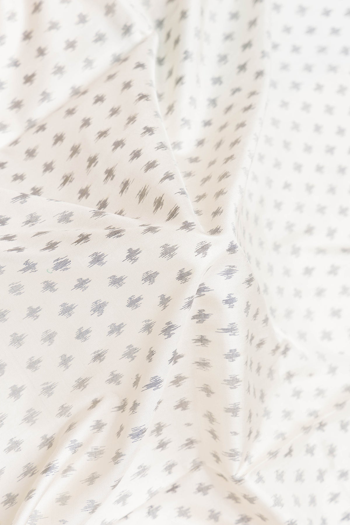 Close up of Off White Dual Tone Double Ikat Saree with Ikat Print on the body and Plain Border.  displaying folds