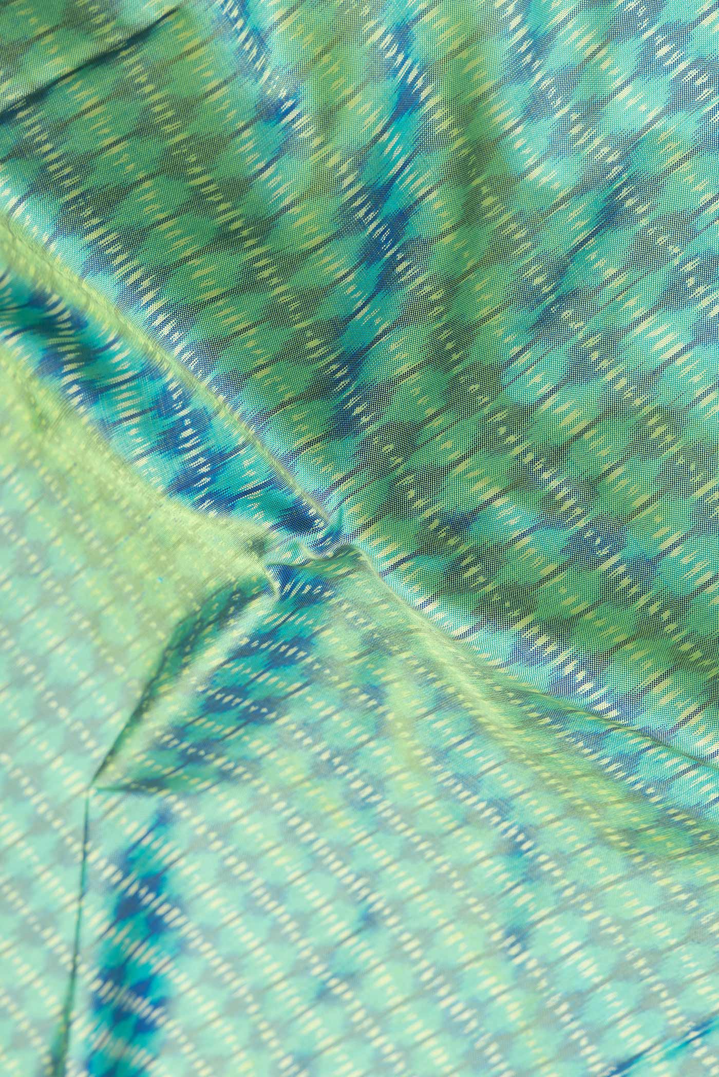 Close up of Green Dual Tone Double Ikat Saree with Ikat Print on the body and Plain Border.  displaying folds
