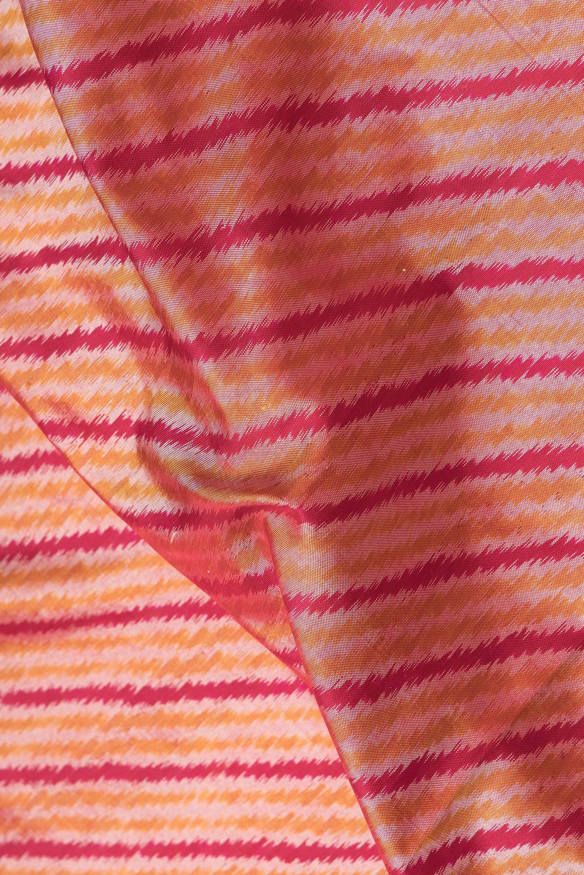 Close up of Maroon Dual Tone Double Ikat Saree with Ikat Print on the body and Plain Border.  displaying folds