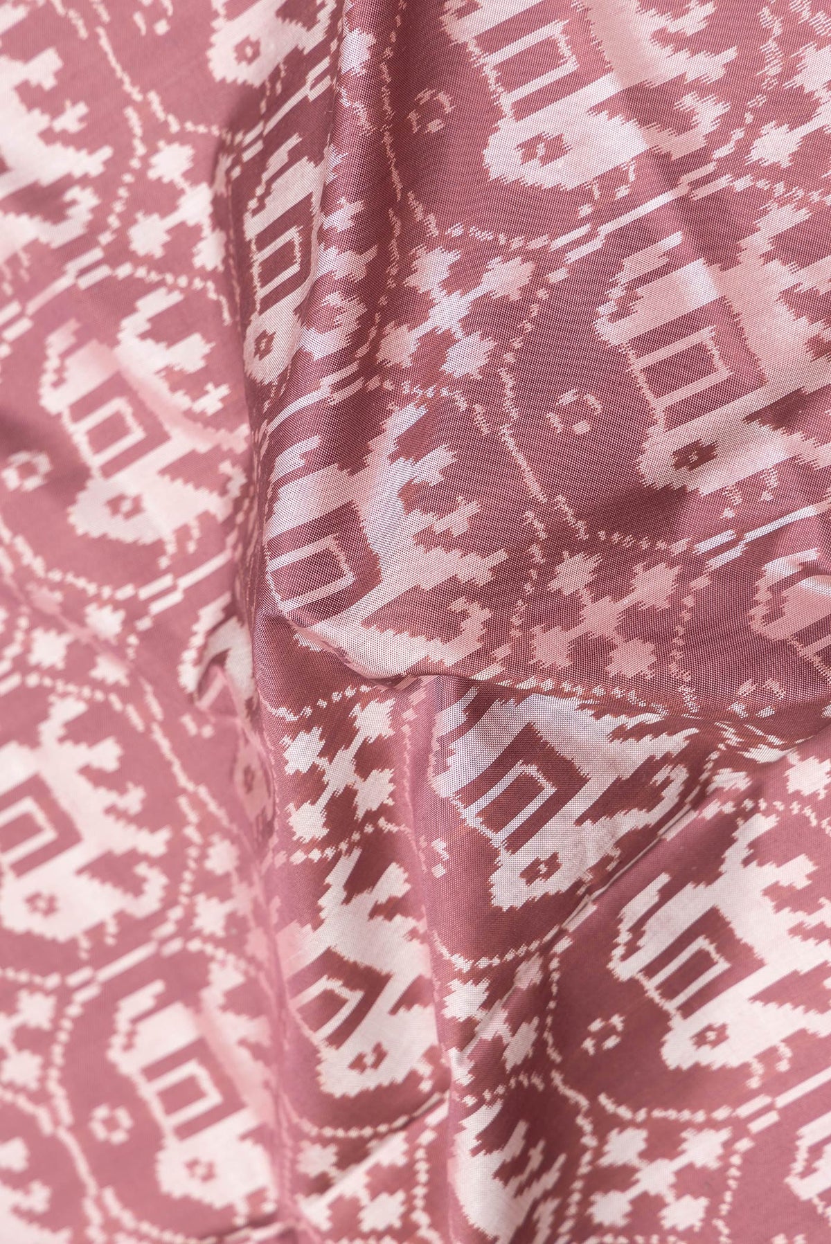 Close up of Brown Dual Tone Double Ikat Saree with Ikat Print on the body and Zari Border.  displaying folds