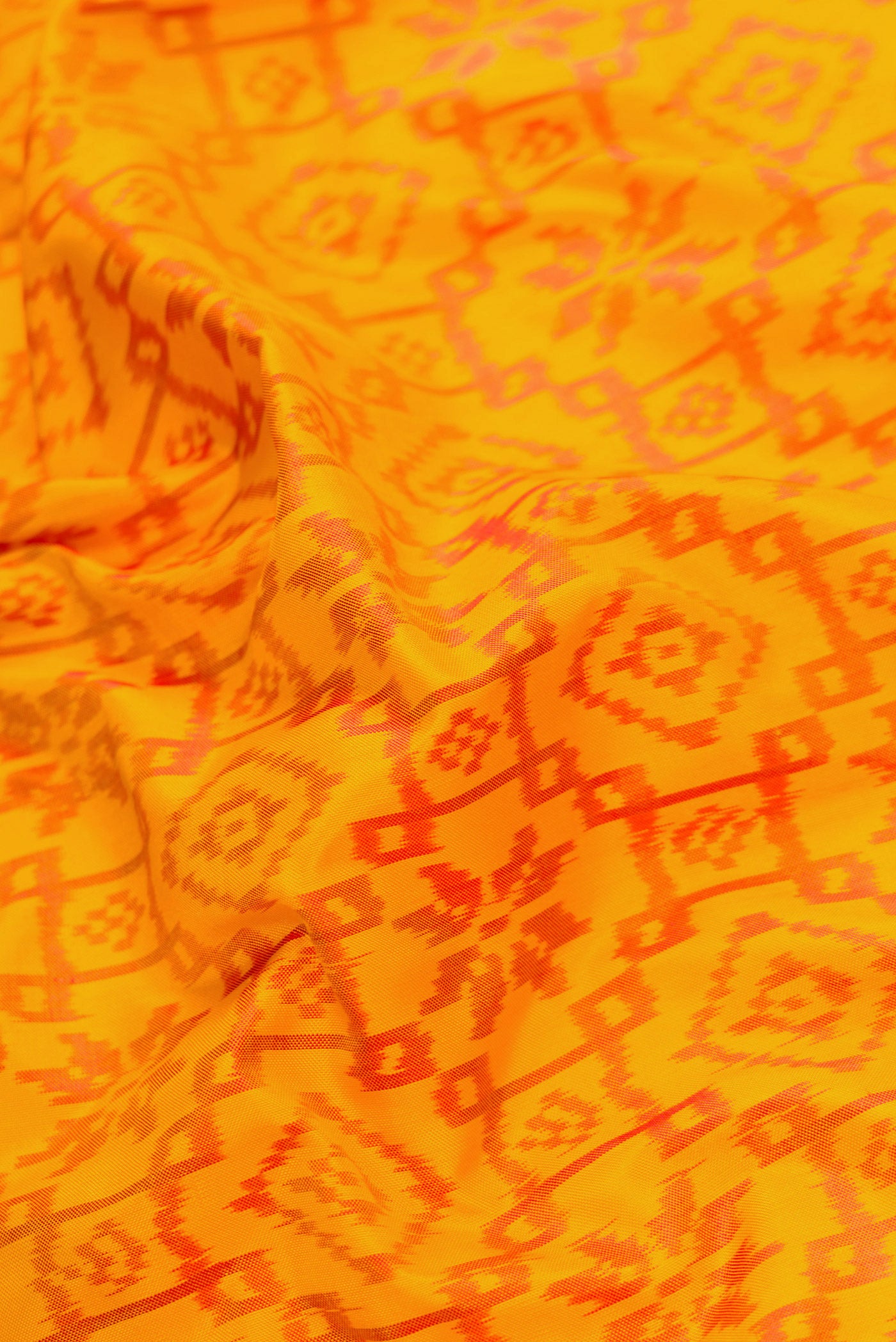 Close up of Mustard Dual Tone Double Ikat Saree with Ikat Print on the body and Zari Border.  displaying folds