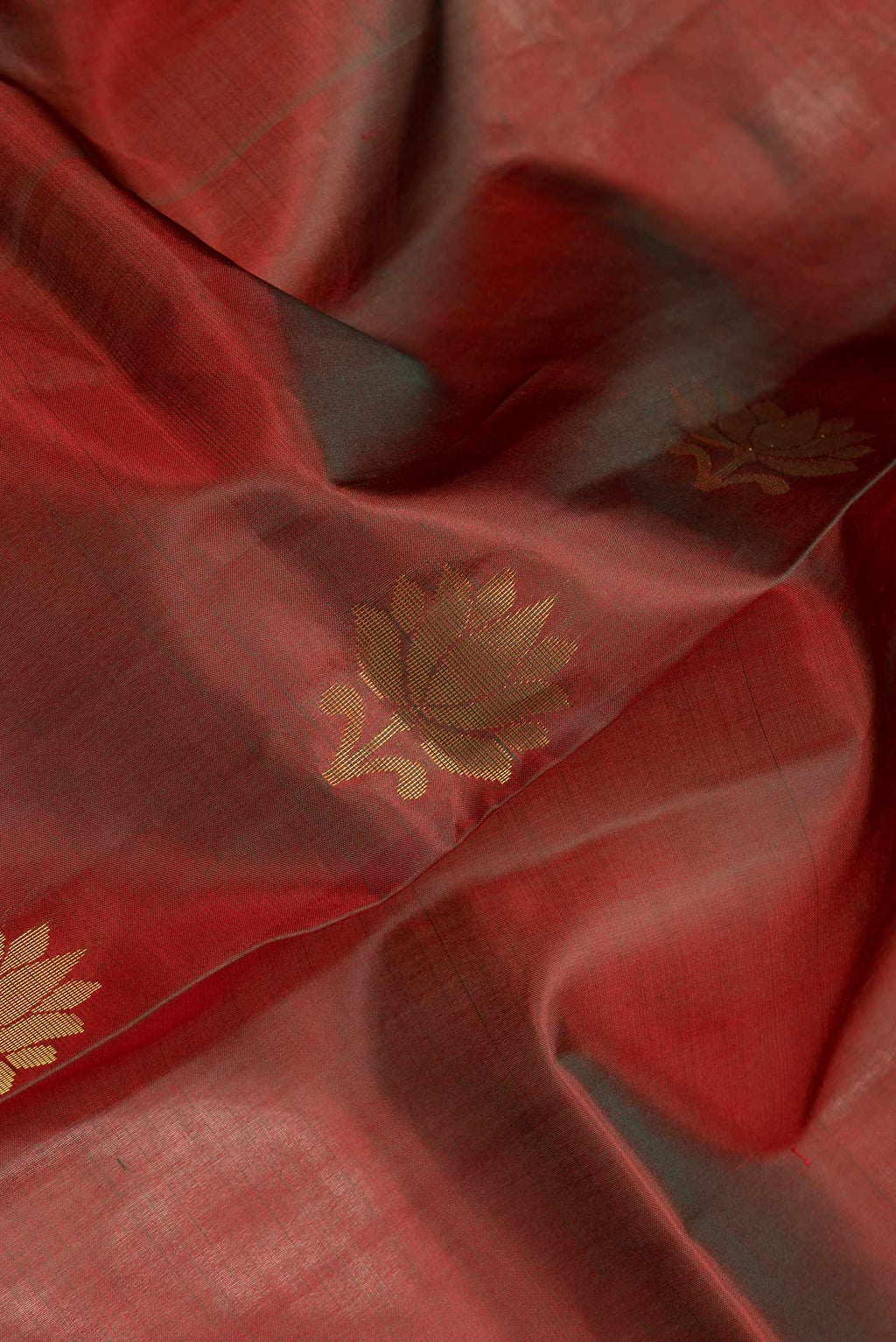 Close up of Maroon Dual Tone Soft Silk Saree with Zari Butta on the body and Zari Border.  displaying folds