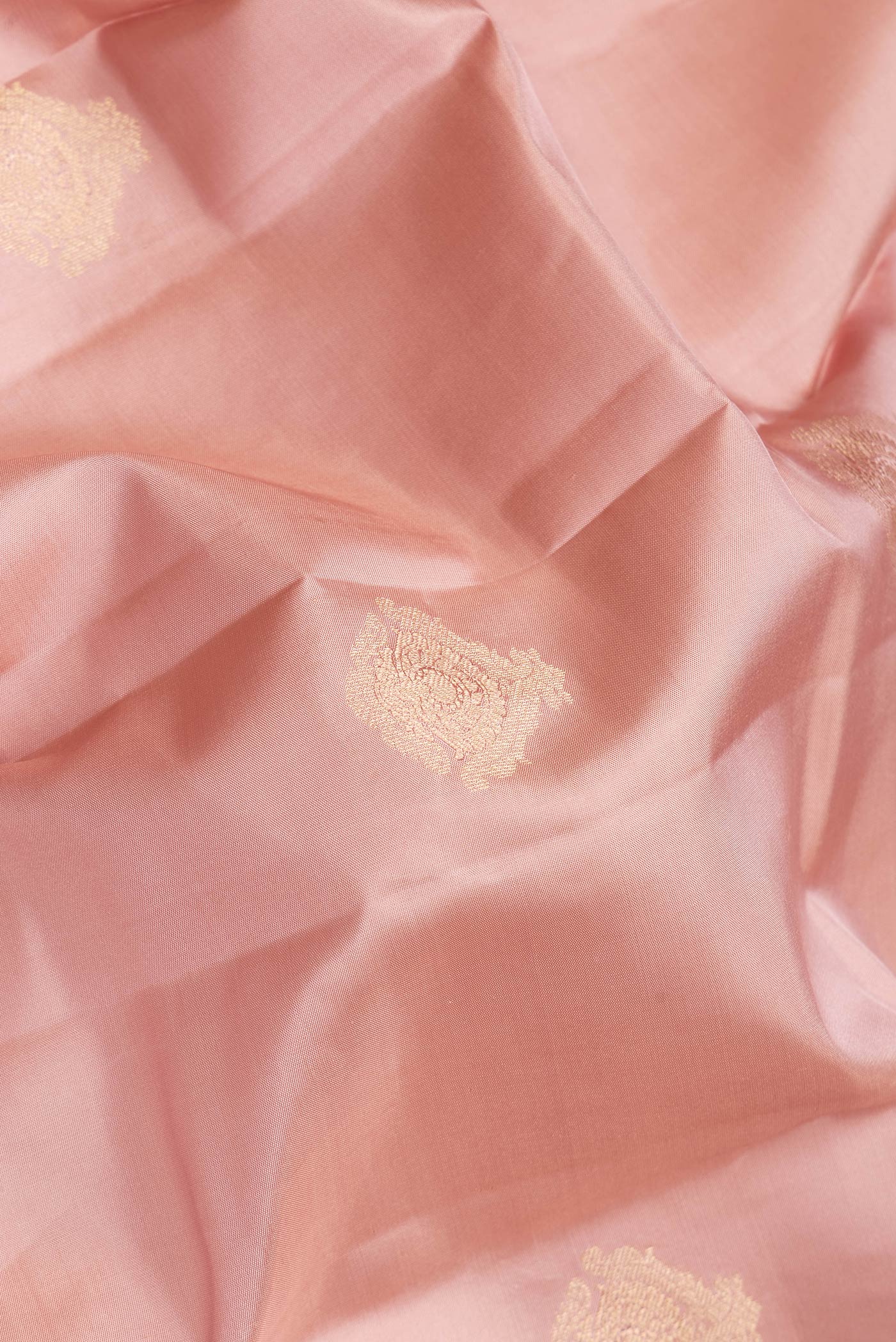 Close up of Rose Gold Dual Tone Kanchipuram Silk Saree with Zari Butta on the body and Zari Border.  displaying folds