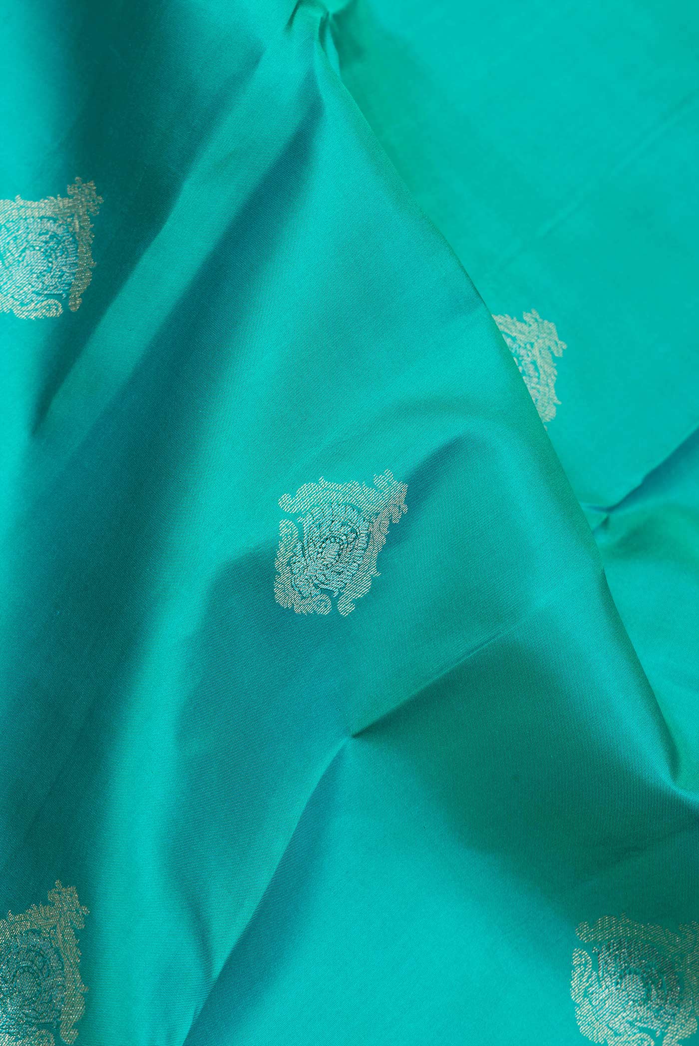 Close up of Green Dual Tone Kanchipuram Silk Saree with Zari Butta on the body and Zari Border.  displaying folds