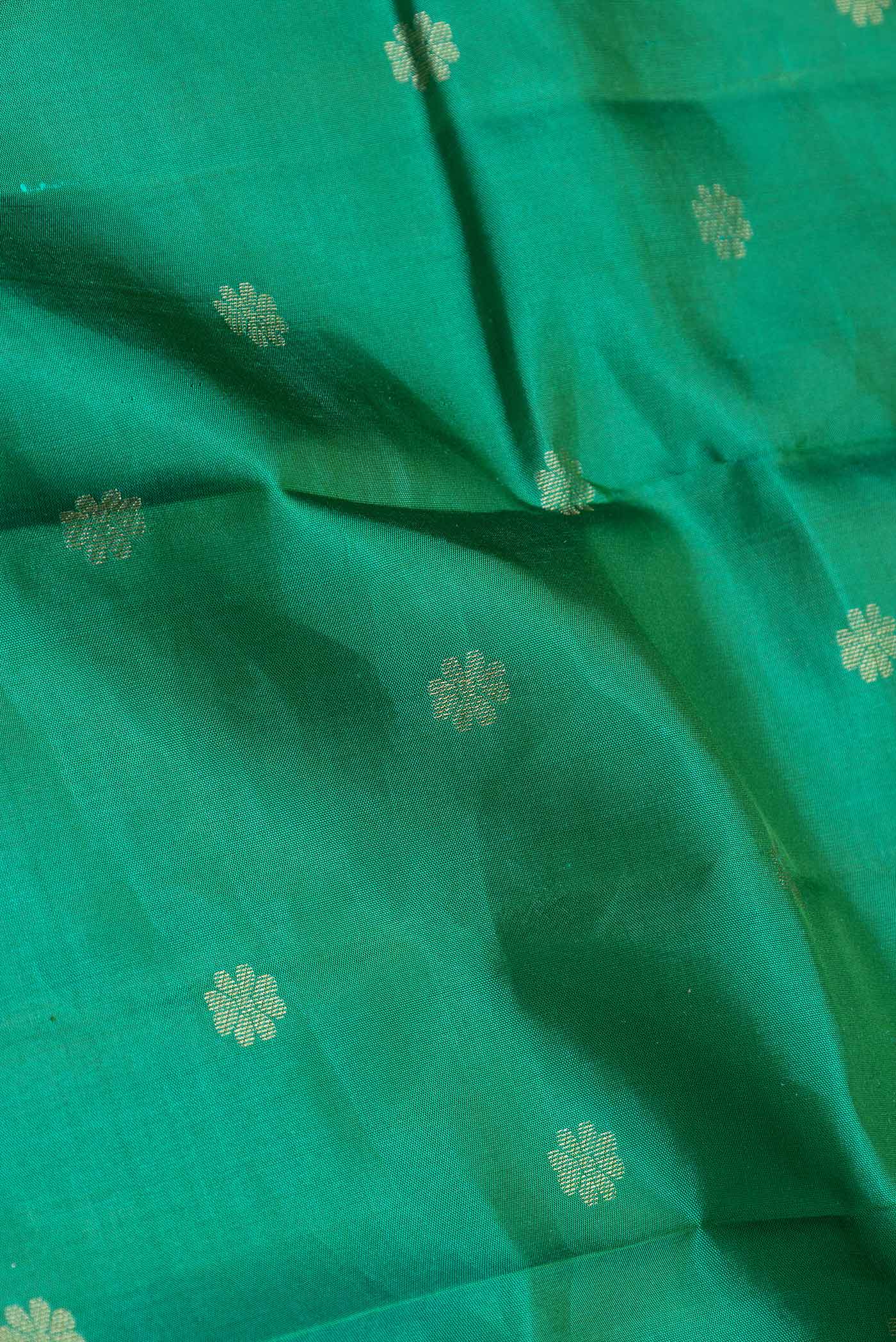 Close up of Green Dual Tone Kanjivaram Silk Saree with Zari Butta on the body and Zari Border.  displaying folds