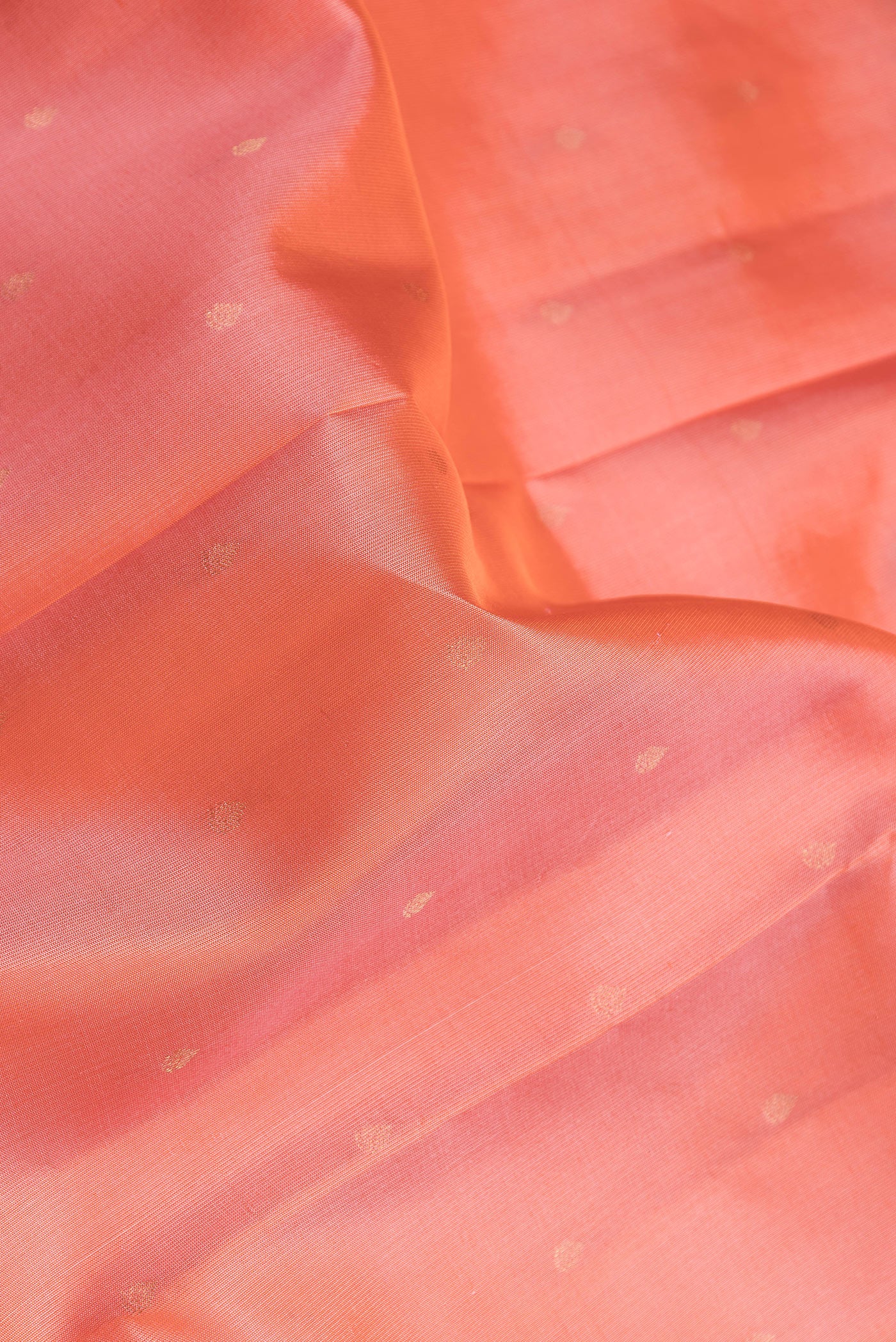 Close up of Peach Dual Tone Kanchipuram Silk Saree with Zari Butta on the body and Zari Border.  displaying folds