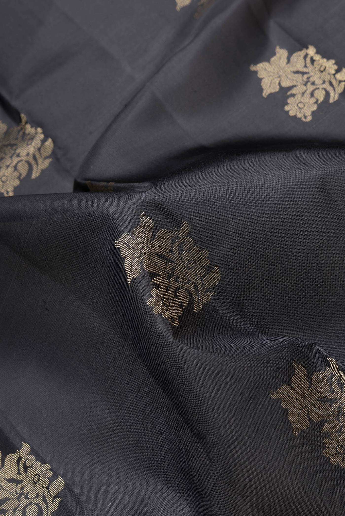Close up of Black Dual Tone Kanchipuram Silk Saree with Zari Butta on the body and Zari Border.  displaying folds