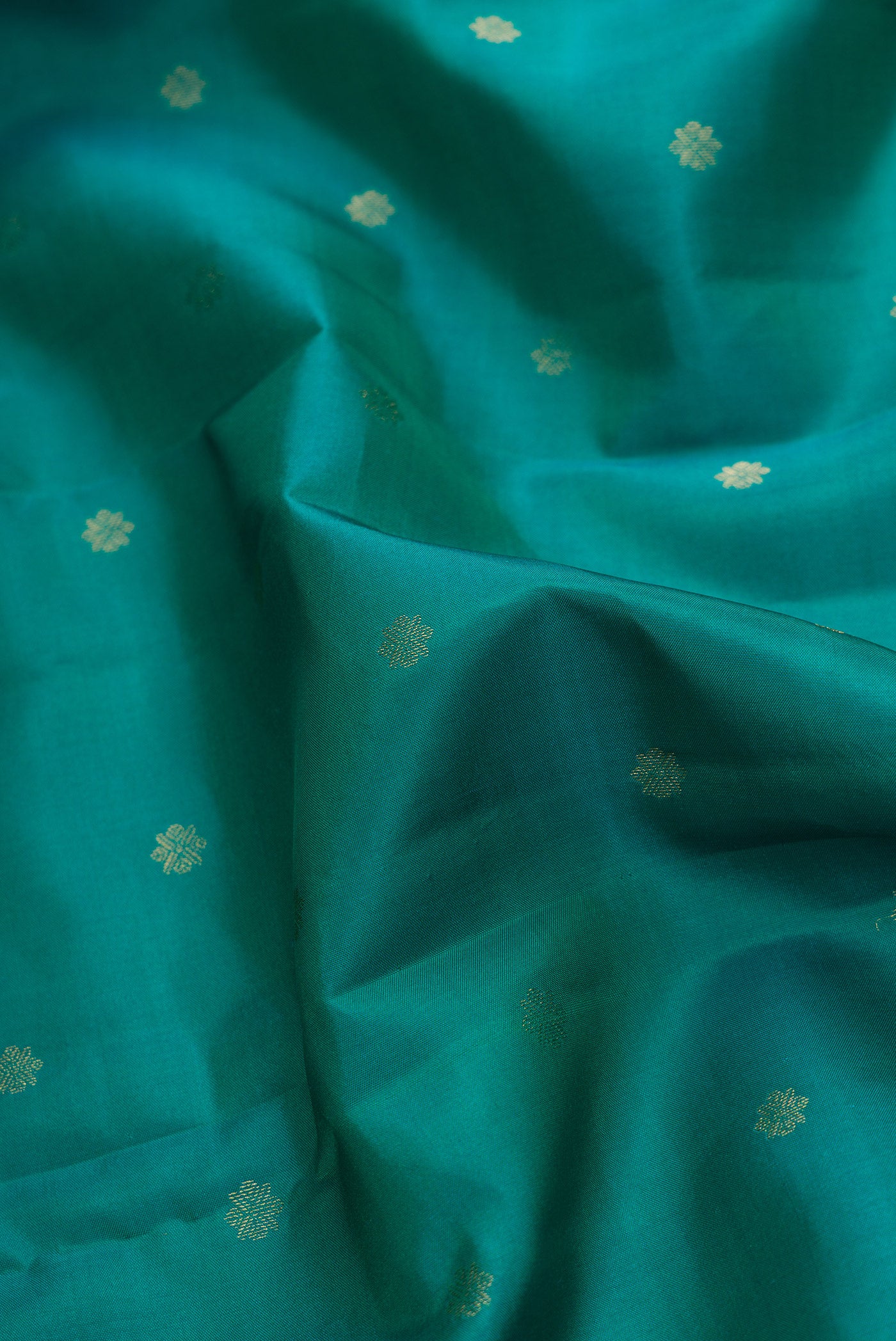 Close up of Green Dual Tone Kanchipuram Silk Saree with Zari Butta on the body and Zari Border.  displaying folds
