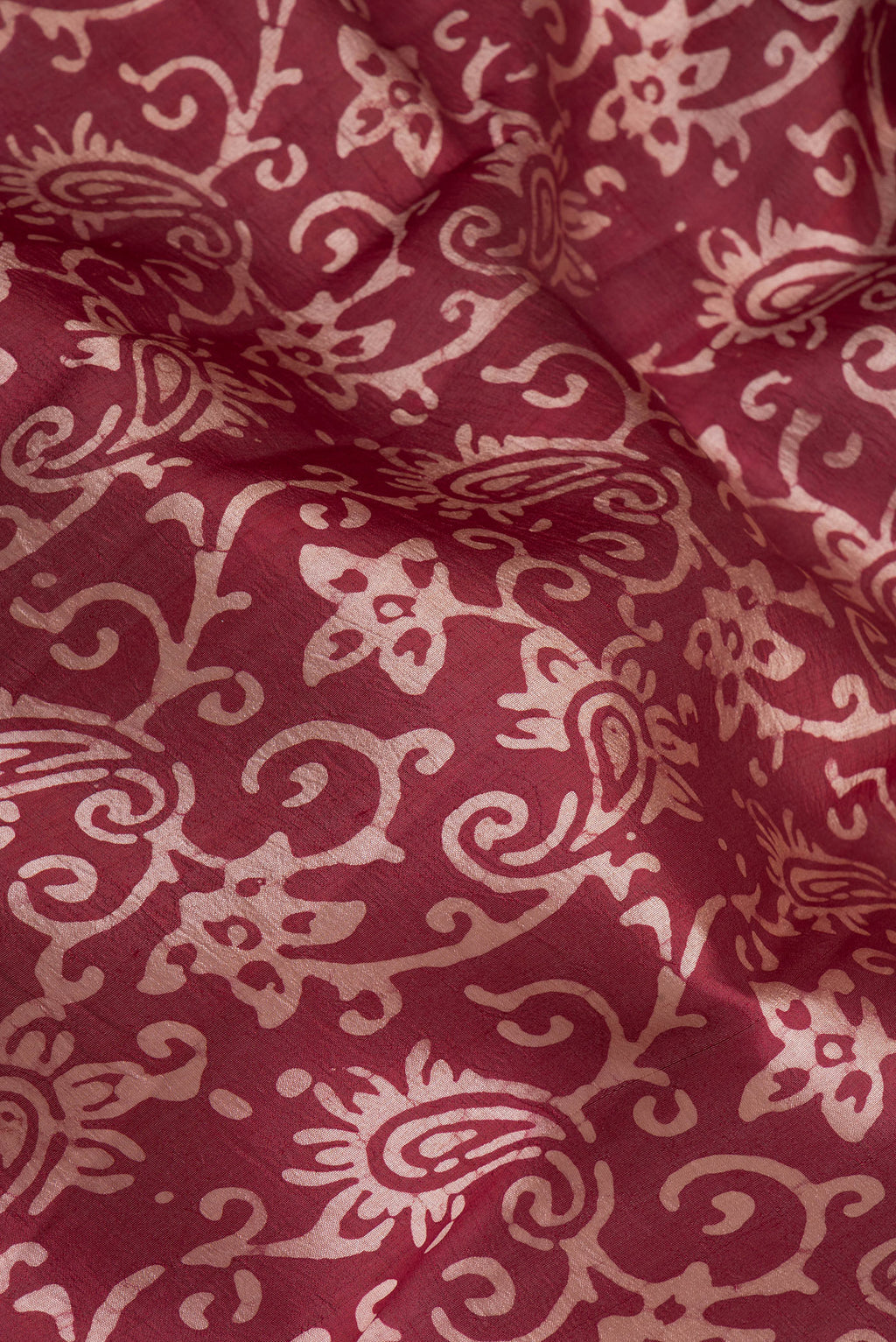 Close up of Maroon Dual Tone Tussar Silk Saree with Batik Print on the body and Printed Border.  displaying folds