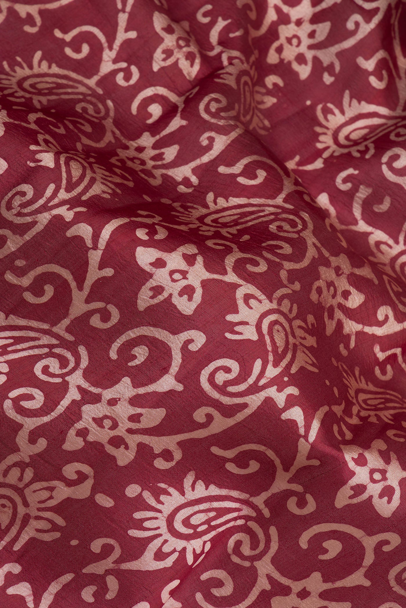 Close up of Maroon Dual Tone Tussar Silk Saree with Batik Print on the body and Printed Border.  displaying folds