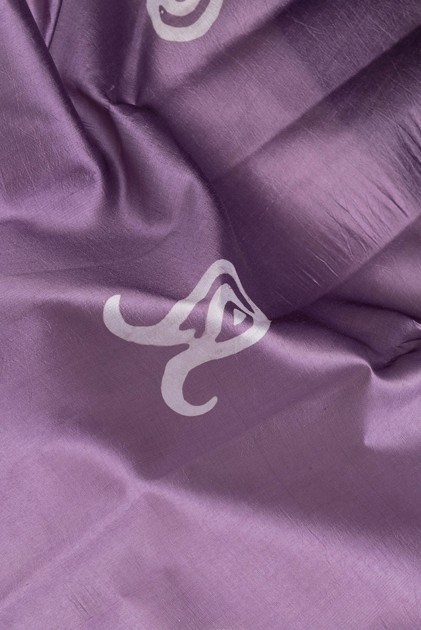 Close up of Lavender Dual Tone Tussar Silk Saree with Batik Print on the body and Printed Border.  displaying folds