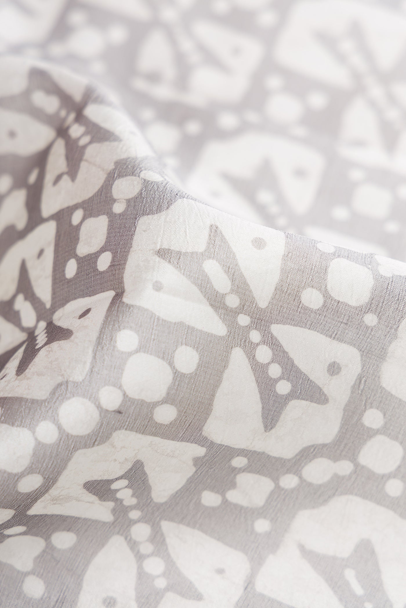 Close up of Grey Dual Tone Tussar Silk Saree with Printed design on the body and Printed Border.  displaying folds