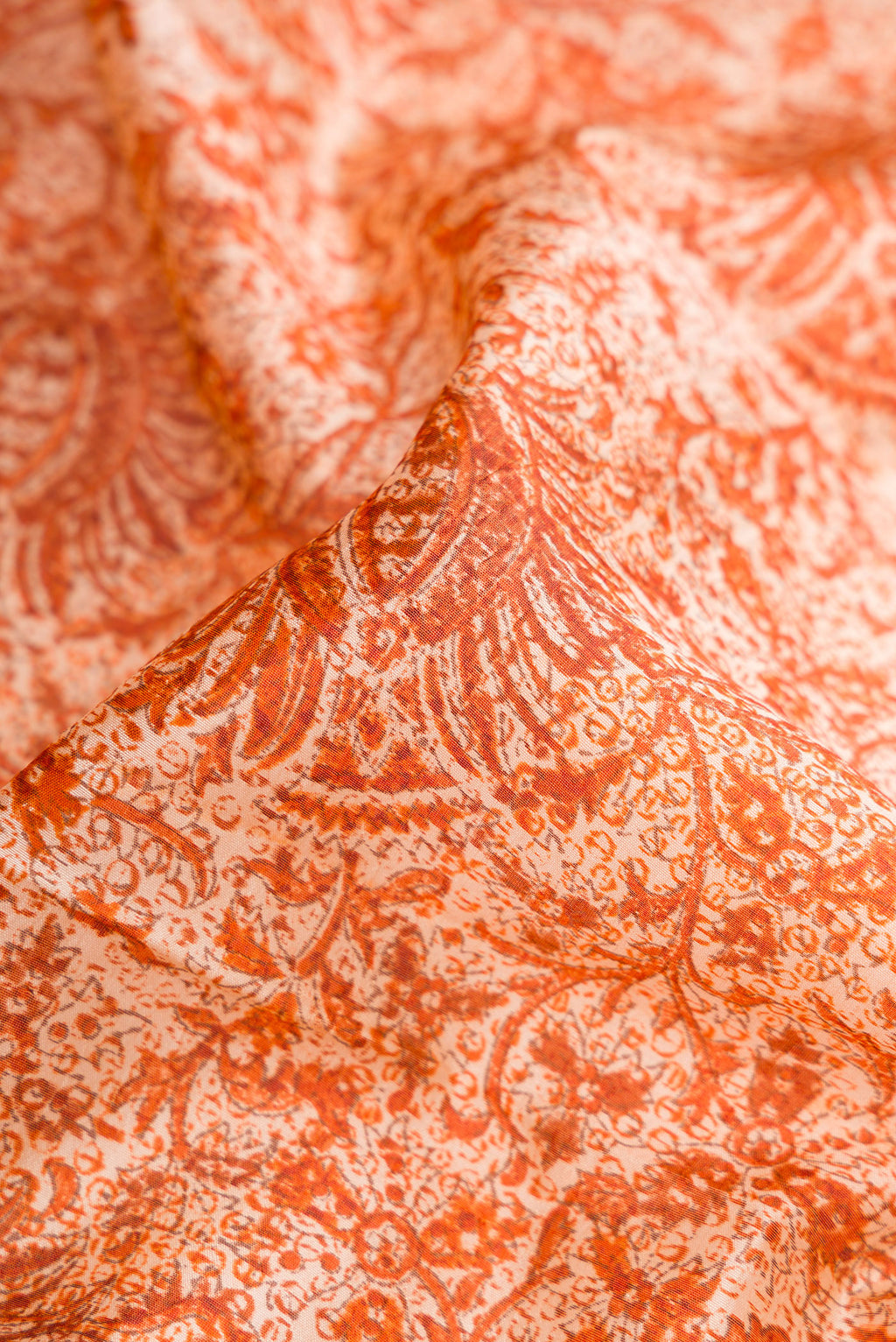 Close up of Orange Dual Tone Tussar Silk Saree with Printed design on the body and Printed Border.  displaying folds