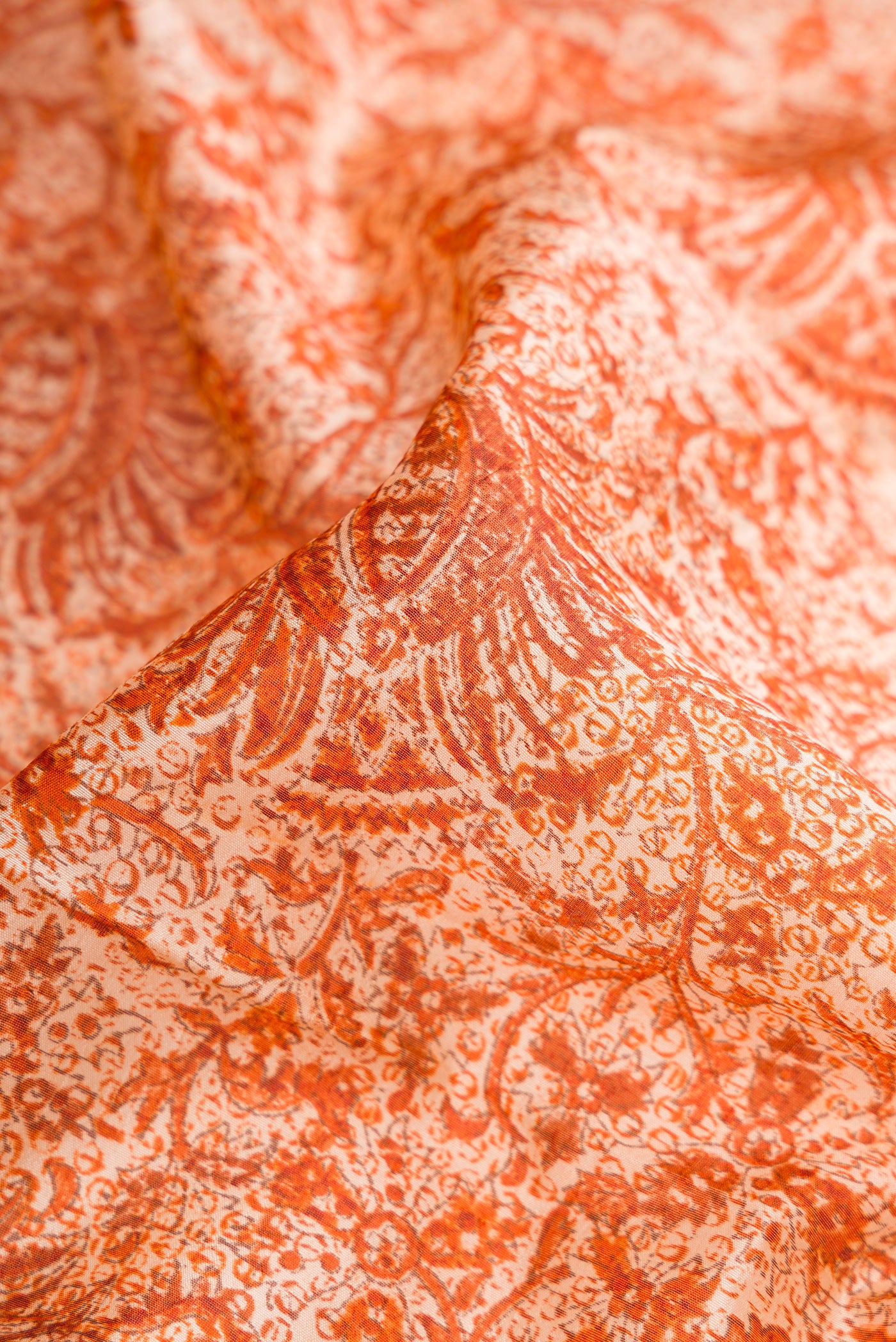 Close up of Orange Dual Tone Tussar Silk Saree with Printed design on the body and Printed Border.  displaying folds
