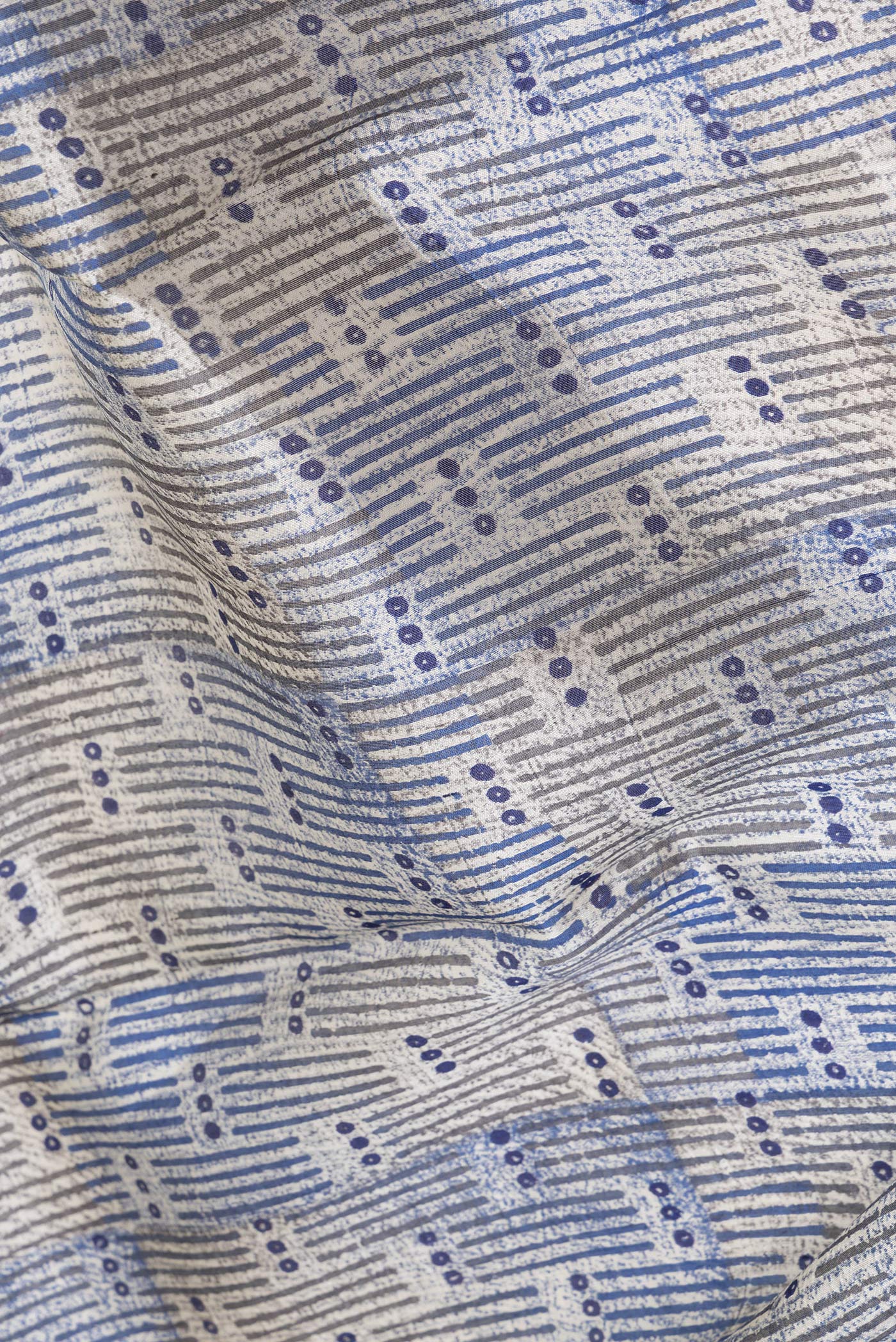 Close up of Beige Tussar Silk Saree with Printed design on the body and Printed Border.  displaying folds